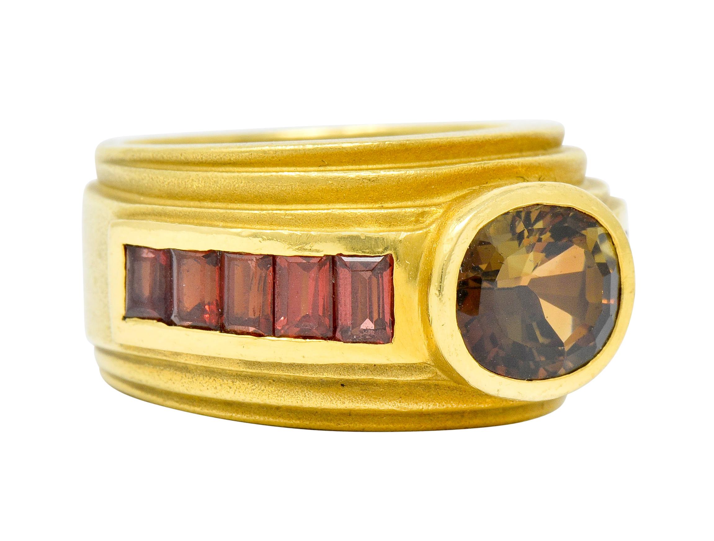Designed as a wide band ring with deeply ridged edges and matte gold finish

Centering a bezel set oval mixed cut andalusite weighing approximately 2.55 carats

Andalusite displays intriguing color of predominantly green body color with flashes of