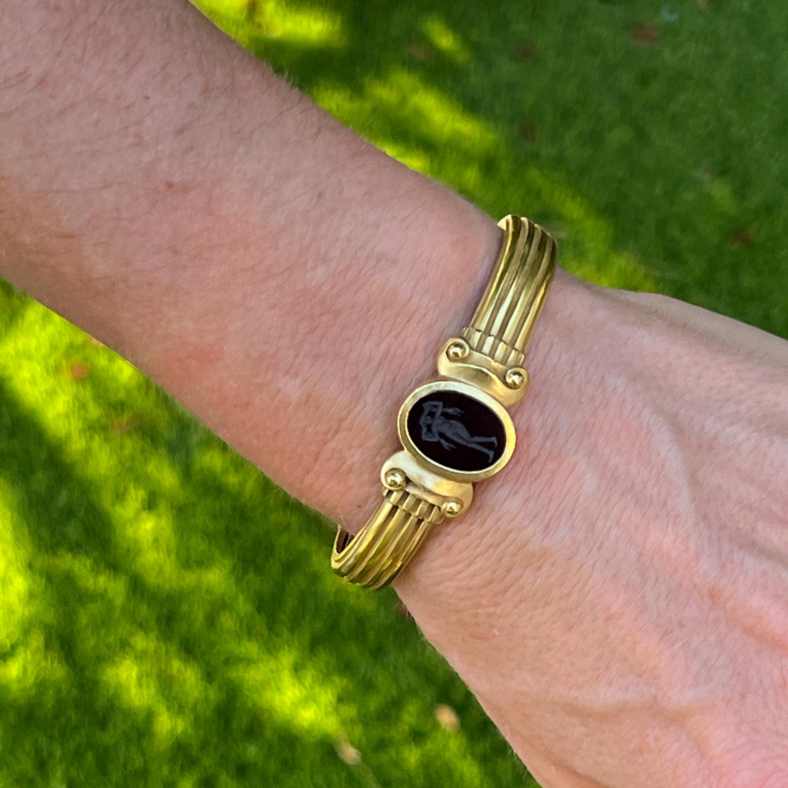 Beautiful black intaglio cuff bracelet by designer Kieselstein-Cord handcrafted in 18 karat yellow gold. The ribbed cuff features an oval onyx black ancient greek intaglio, and hinged ends for easy wear. The cuff measures 10-15mm in width, and 2.25