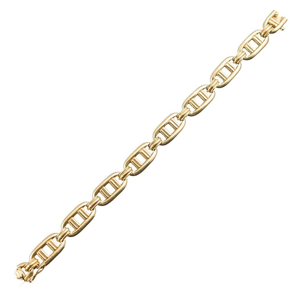 Attractive and substantial, this bracelet measures a generous 8 inches long and is finished with a single safety. Each oval link is hallmarked on the back side and connected by a golden three-ridged bridge. This weighty piece is made of 18 karat