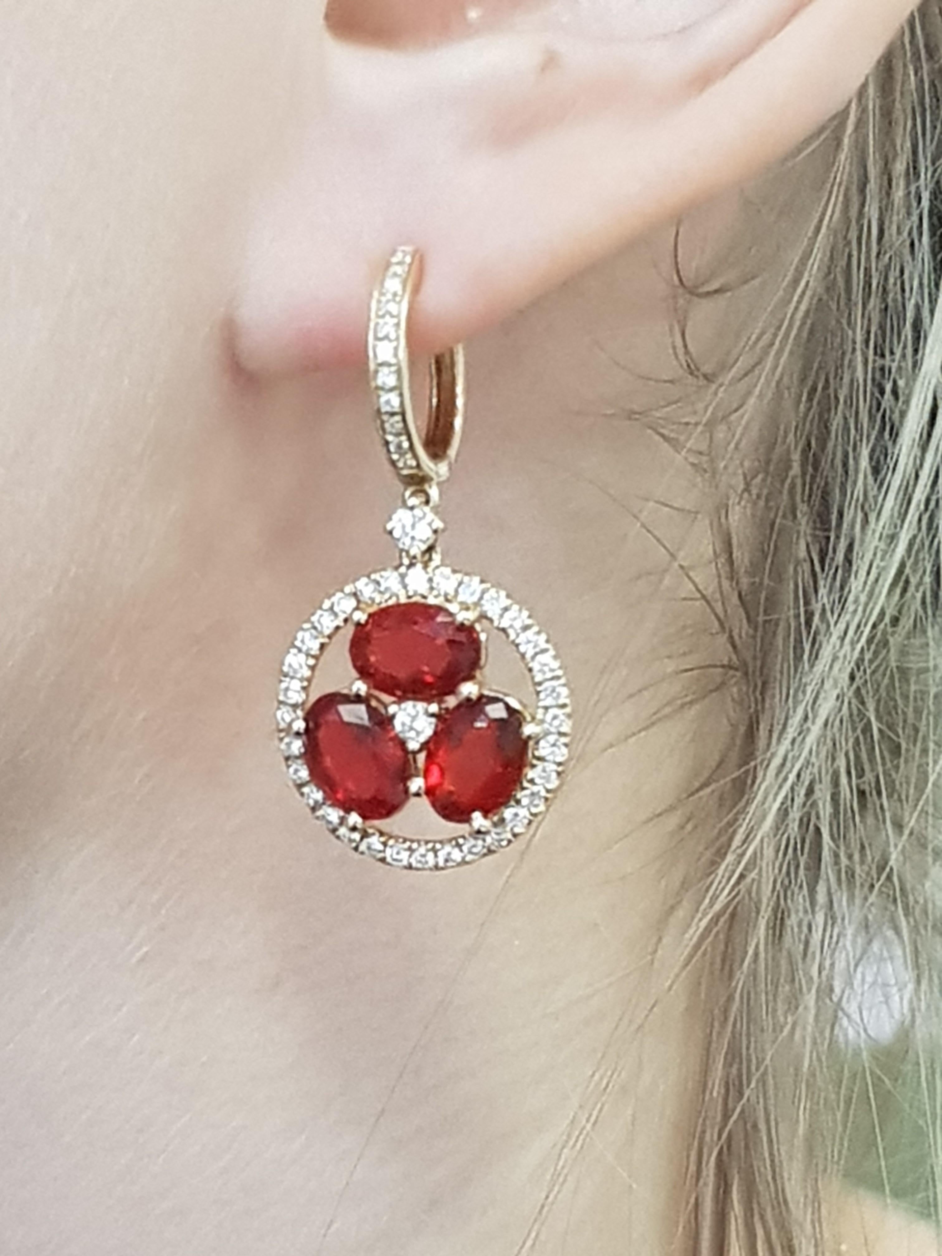 These vibrant drop earrings feature three central Fire Opal Stones (3.4cts), set in 18 Karat Yellow Gold, that are surrounded by a ring of Diamonds and hang from a Diamond hoop.