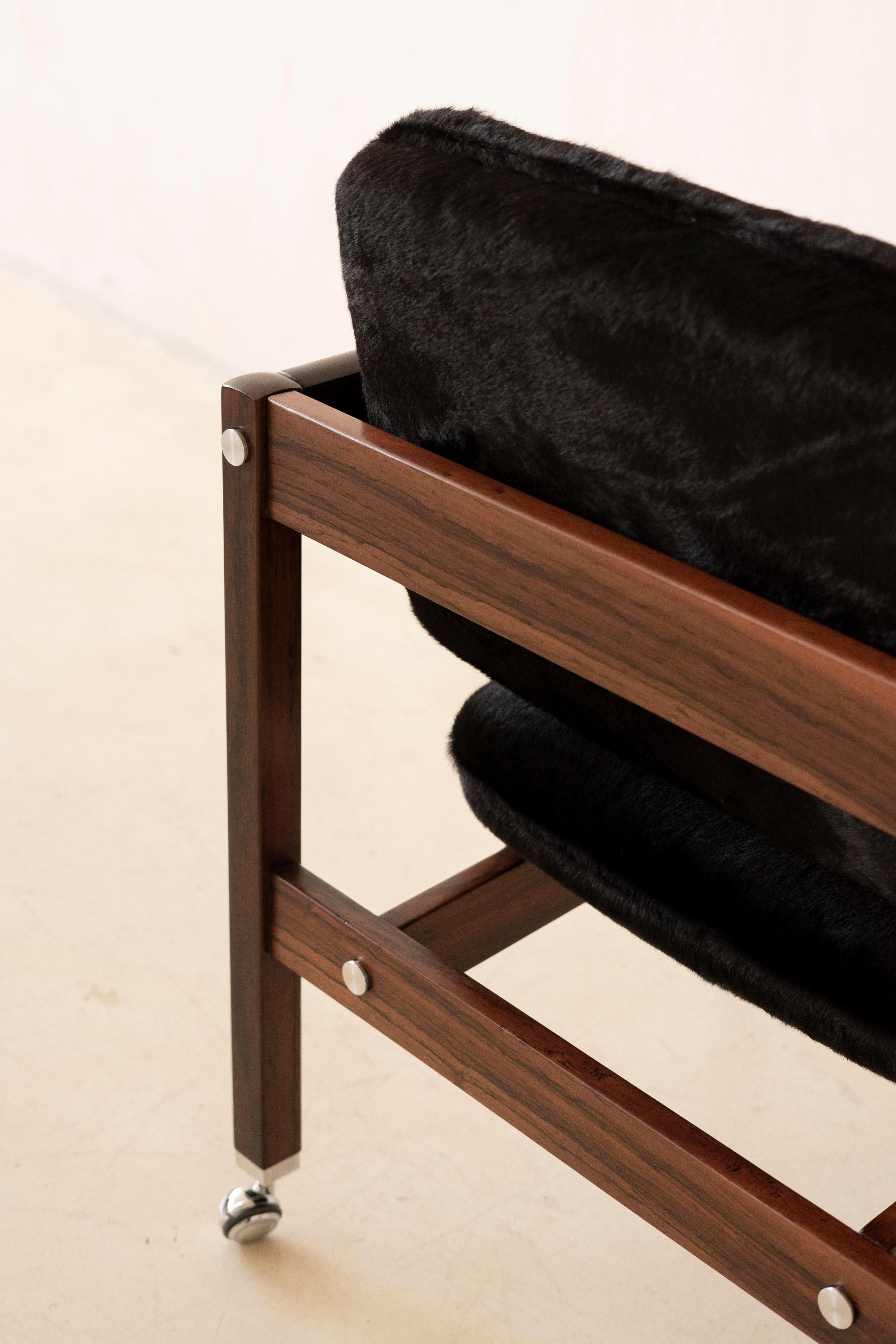 Disponible con o sin ruedas, Kiko está hecho de palisandro macizo y tiene asiento y respaldo tapizados. Sergio Rodrigues (1927-2014) creó el Sillón Kiko en 1964 para el Palacio de Itamaraty, sede del Ministerio de Asuntos Exteriores de Brasil. El