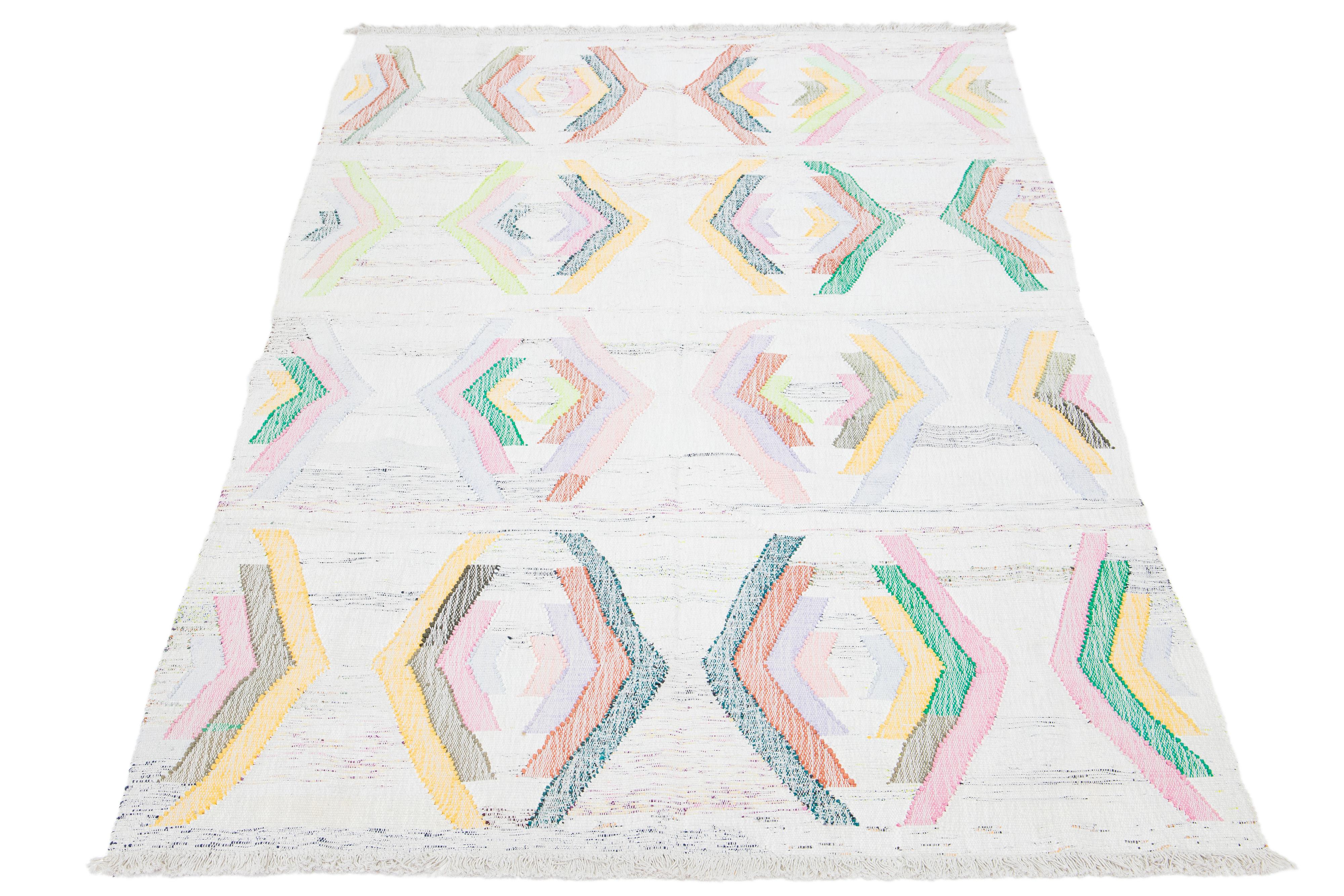 Dieser Teppich zeichnet sich durch ein modernes Kilim-Flachgewebemuster aus Wolle aus. Er hat einen beigen Untergrund mit einem geometrischen Muster in verschiedenen Farben.

Dieser Teppich misst 6'5