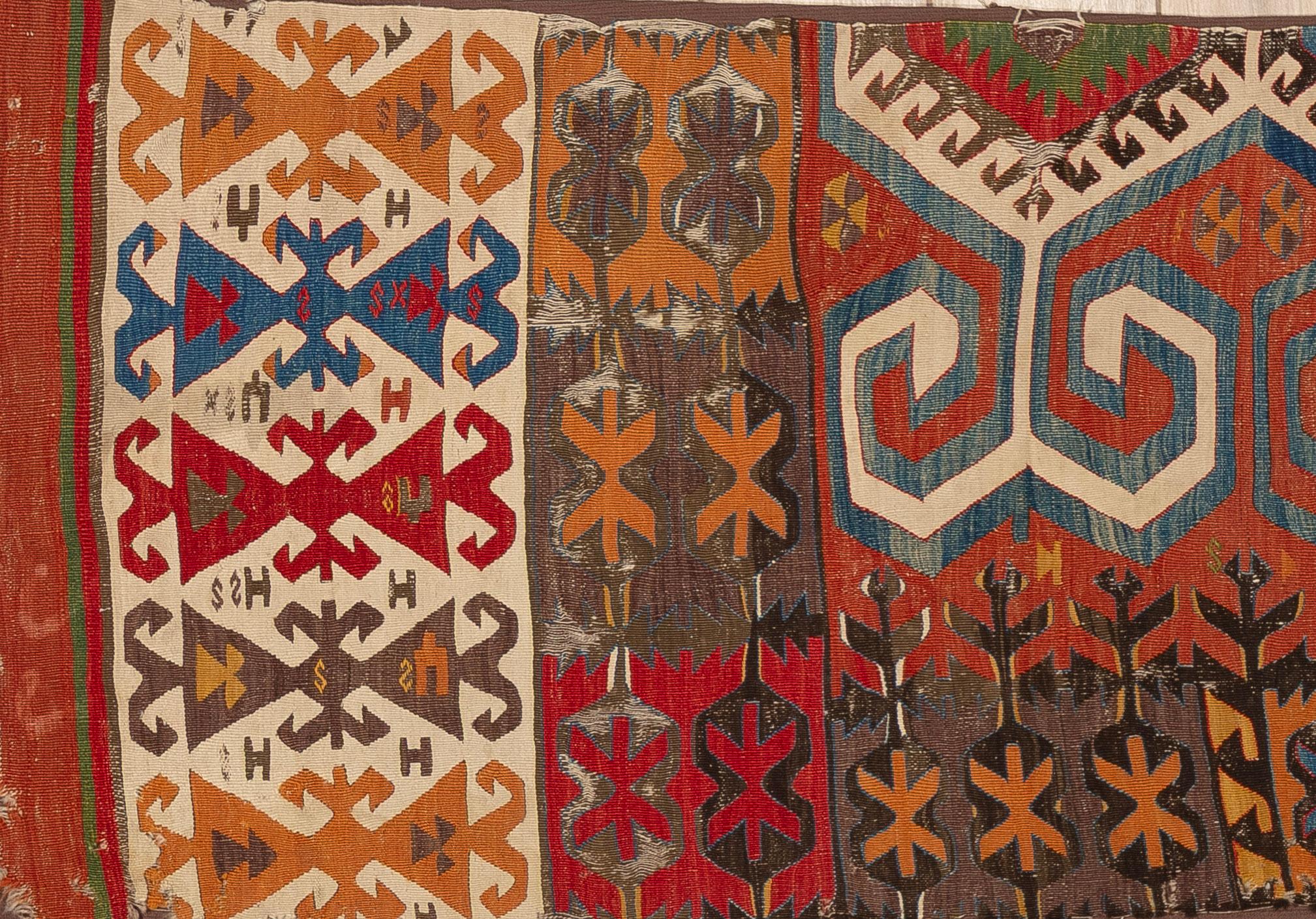Ce kilim tribal coloré est un tissage plat vibrant qui reflète la créativité et l'héritage du tissage nomade traditionnel. Tissé à la main en laine, il présente des motifs géométriques audacieux et des motifs répétitifs qui symbolisent la