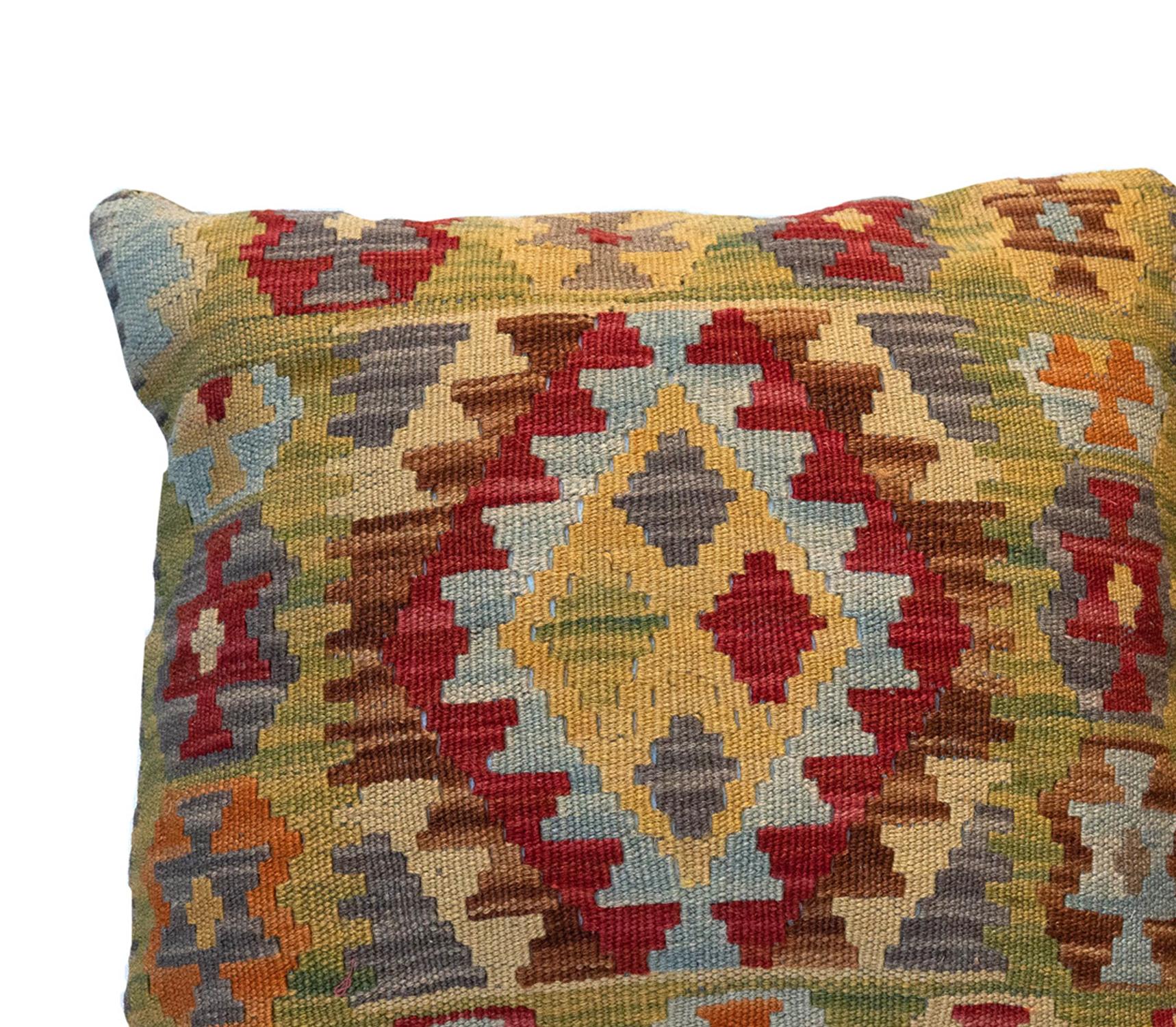 This truly unique geometric cushion cover is a handwoven kilim cushion cover woven in Afghanistan in the late 20th century/ early 21st century. Woven with an elegant geometric design with a bold colour palette of green, red and beige. The colours