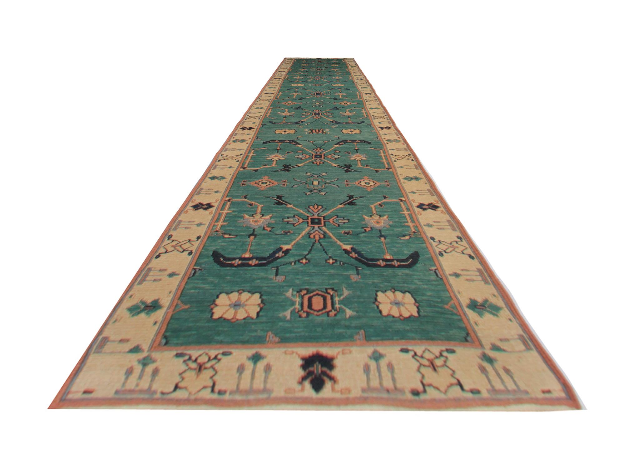 This is a Sumakh tribal rug features a green background with a repeating pattern all-over the body of the woven rug. The green rug is a flat-weave rug, woven with the finest quality wool and cotton. The handmade carpet rug has pink, yellow, khaki