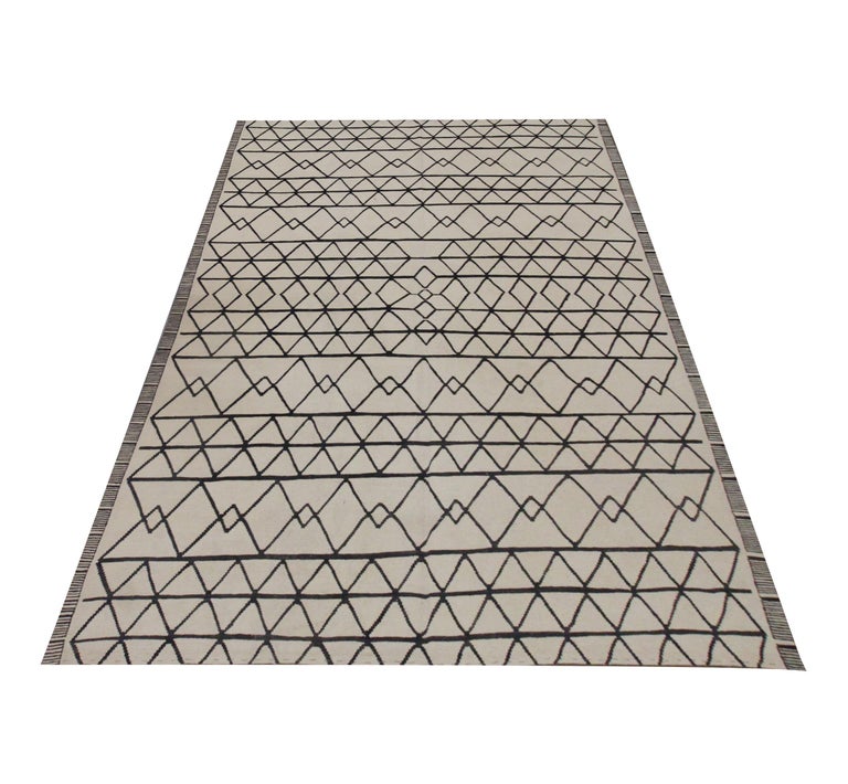 This fine wool Kilim is a modern rug woven with a Scandinavian rugs style in a simple colour palette of cream and black. The black accents make up the symmetrical geometric pattern, creating a bold, eye-catching rug. Similar to the Scandinavian