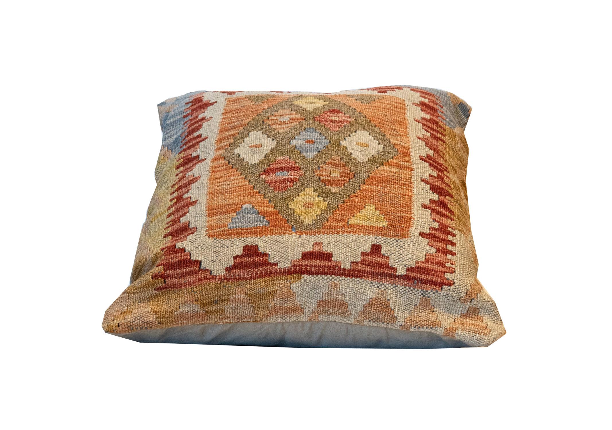 This truly unique geometric cushion cover is a handwoven kilim cushion cover woven in Afghanistan in the late 20th century/ early 21st century. Featuring a bold colour palette and geometric design made up of rust, brown, red and blue accents. Both