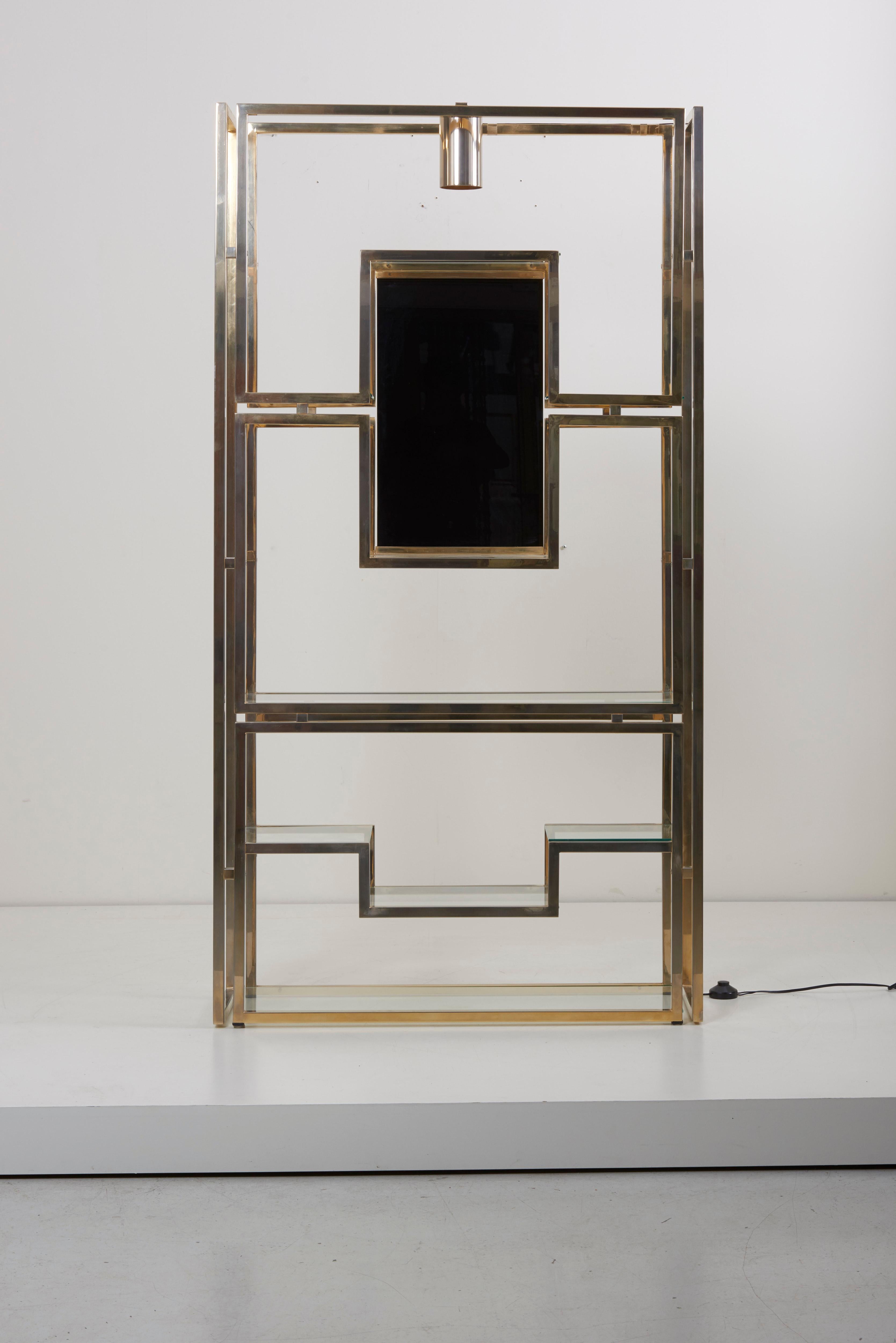 The silvered and brass finish metal frame, centered with black glass panel, brass light and eight clear glass shelves.