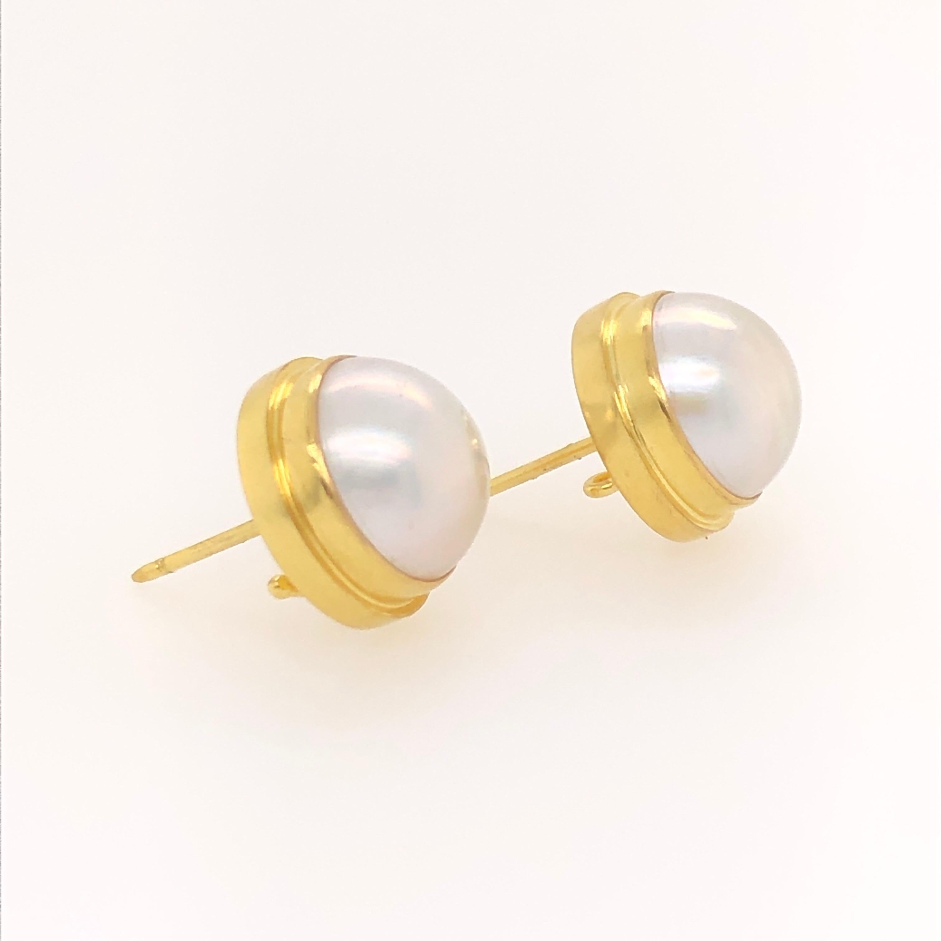This pair of Kimarie earring studs feature two 13 millimeter mabe pearls set in 18K yellow gold. The setting themselves have a hook from which charms can be attached making them super versatile. Wear them with your favorite jeans and a white t-shirt