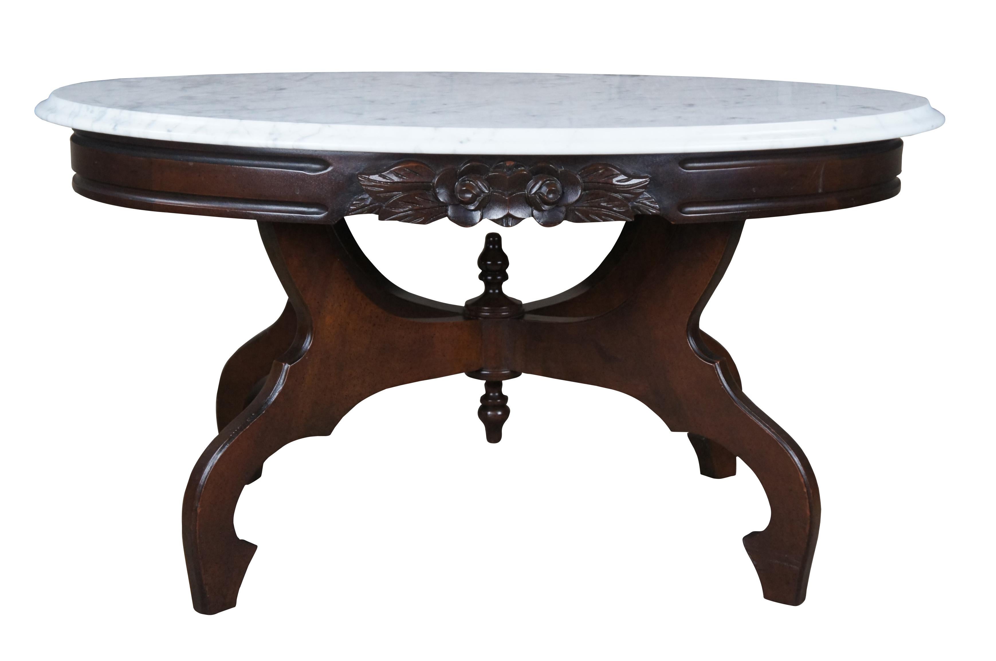 Vintage Victorian Revival parlor table by Kimball Furniture. Made from mahogany with an oval white Italian marble top. Features a rose carved apron over a four legged base centered by finials. Measure: 34