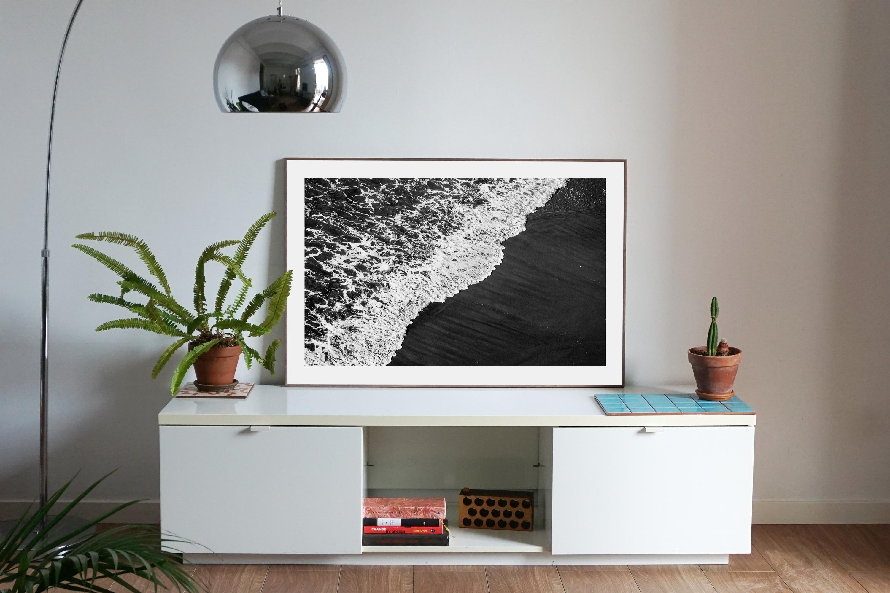 Shore de sable noir profond, paysage marin noir et blanc, vague éclatante qui attire sur la côte - Minimaliste Photograph par Kind of Cyan
