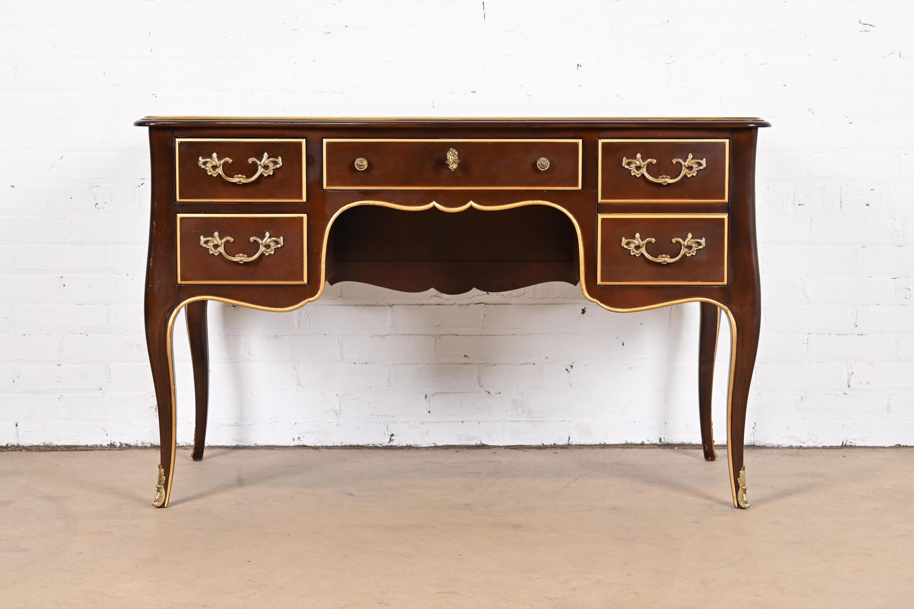 A gorgeous French Provincial Louis XV style bureau plat writing desk

By Kindel Furniture 

USA, Circa 1960s

Mahogany, with gold gilt trim, mounted brass ormolu, and original brass hardware. Middle drawer locks, and key is