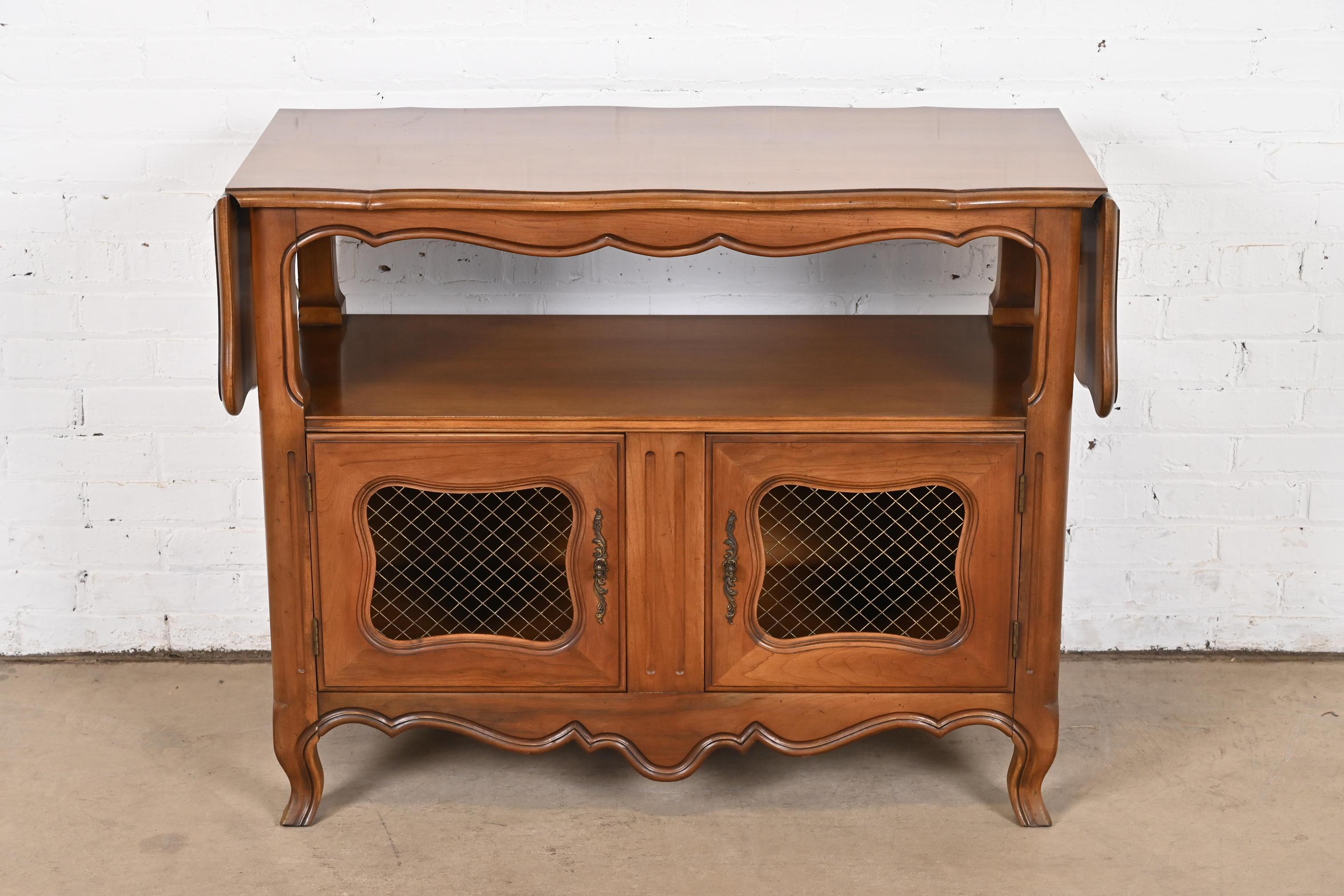 A beautiful French Provincial Louis XV style drop leaf buffet server or bar cabinet

By Kindel Furniture

USA, Circa 1970s

Carved cherry wood, with original brass hardware.

Measures: 41