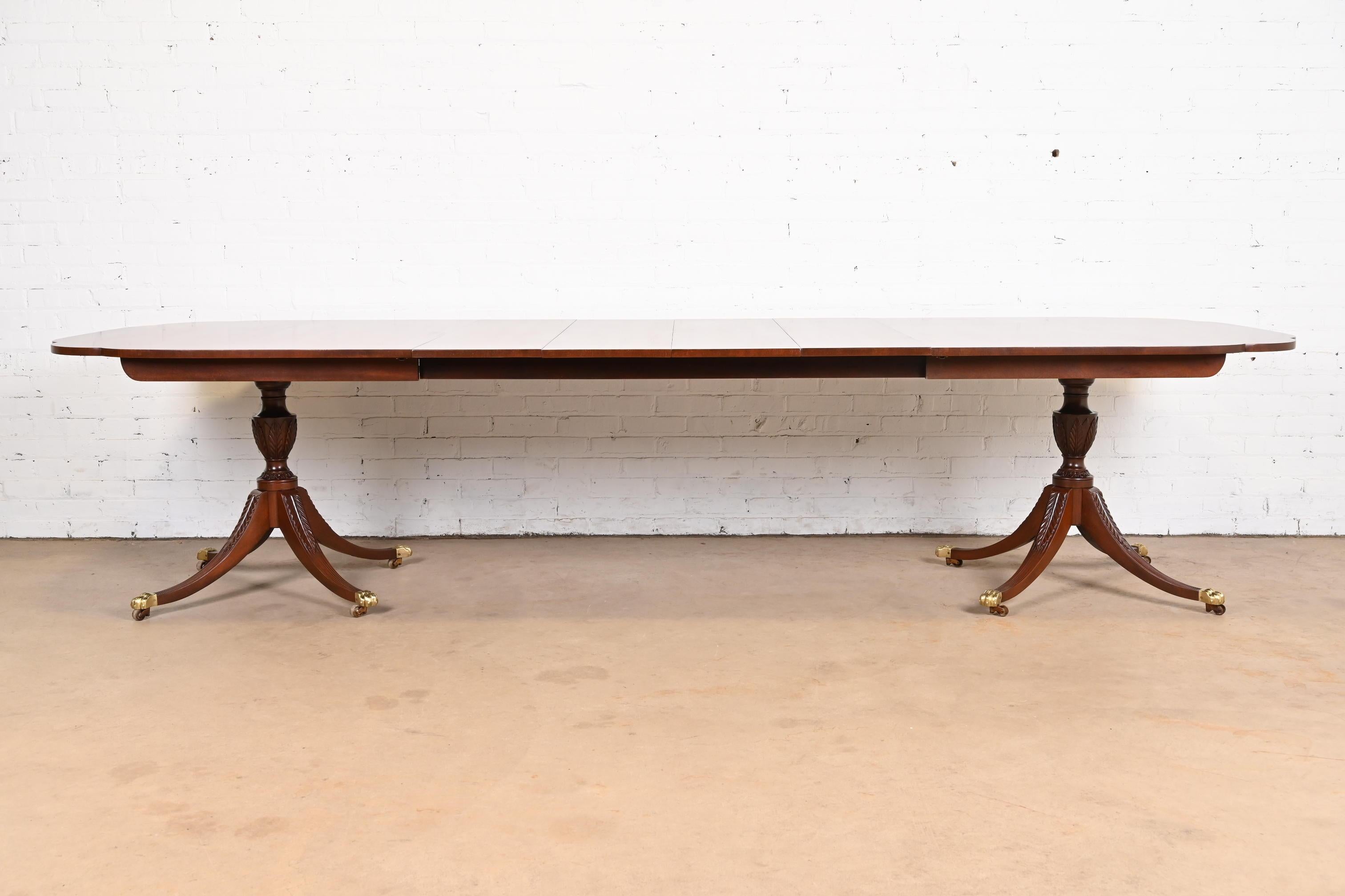 Magnifique table de salle à manger à double piédestal de style géorgien ou régence.

Par Kindel Furniture

USA, Circa 1980

Acajou massif, coins festonnés, piédestaux sculptés, pieds en patte de laiton et roulettes en laiton. Un design unique, avec