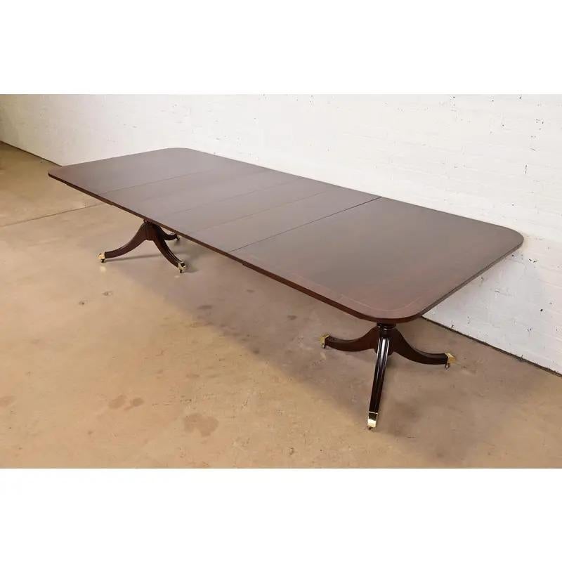 Uno splendido tavolo da pranzo allungabile con doppio piedistallo in stile Georgiano o Regency

Da Kindel Furniture

USA, circa anni '1980

Mogano a fasce, con intarsio di corde in legno di raso, piedistalli in mogano massiccio intagliati e piedi