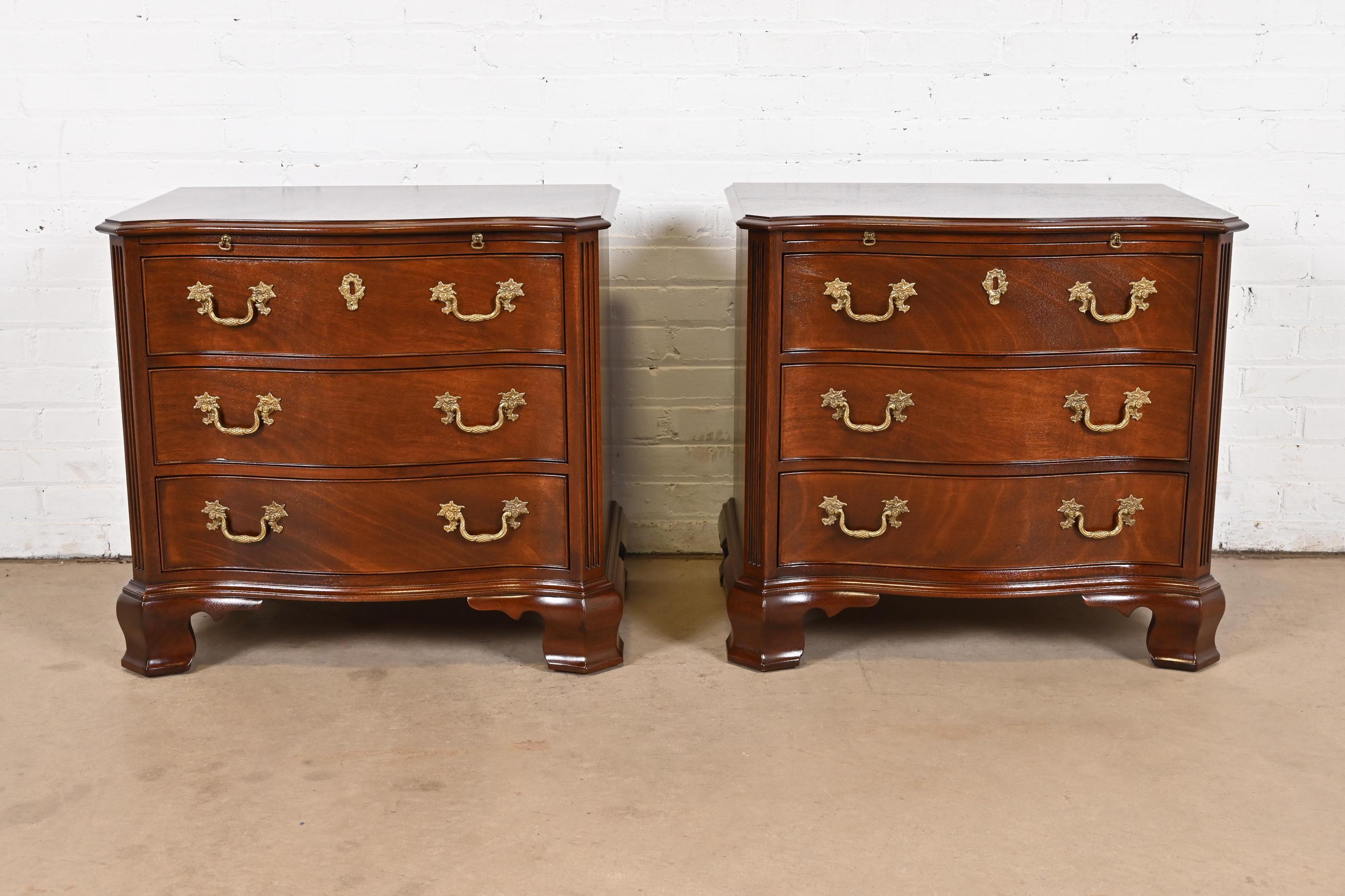 A gorgeous pair of Georgian or Chippendale style serpentine front three-drawer bedside chests or bachelor chests with pull-out writing tablet

By Kindel Furniture

USA, Circa 1980s

Beautiful solid carved mahogany, with original brass