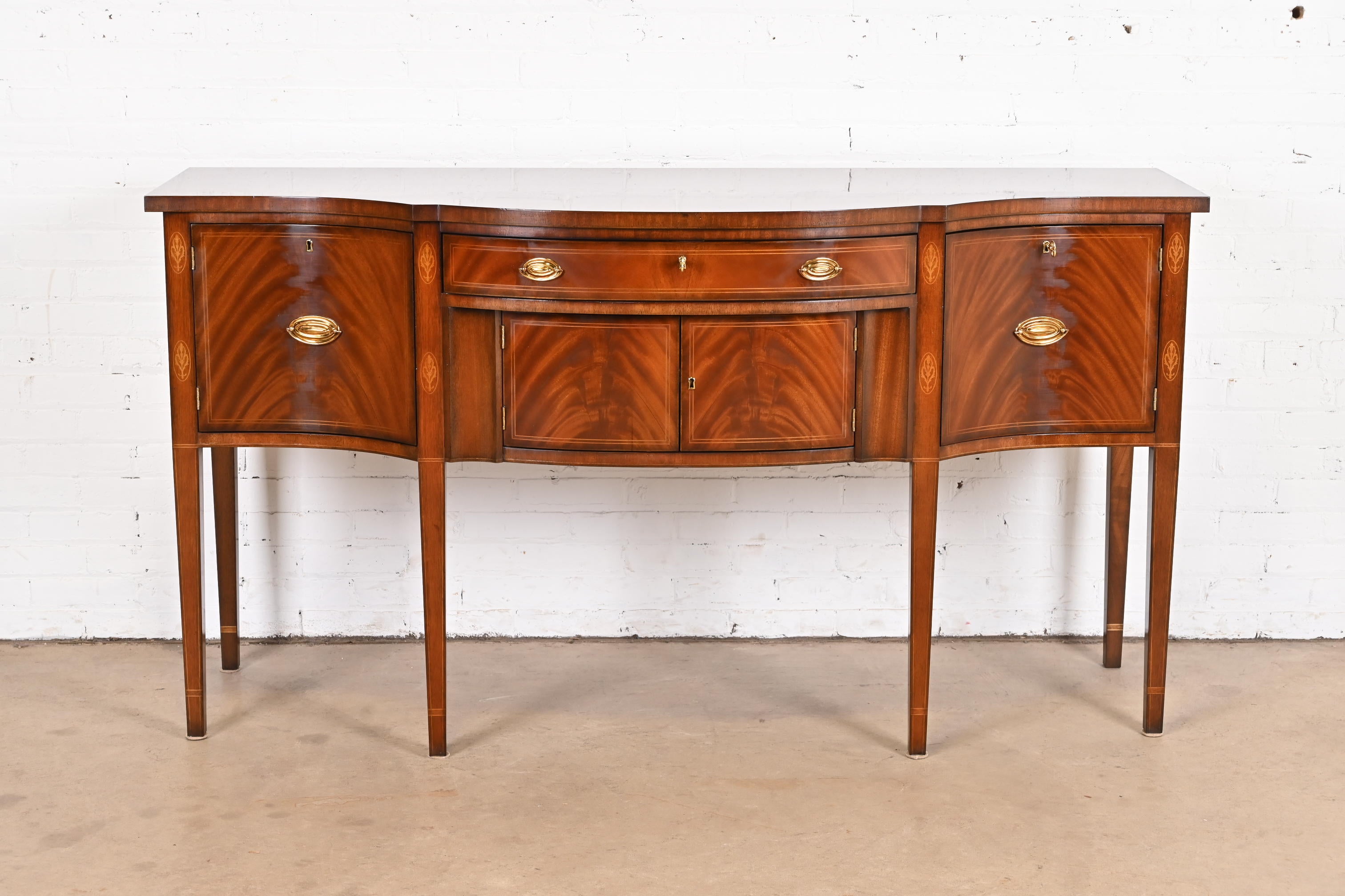 A gorgeous Hepplewhite or Federal style bow front sideboard buffet or credenza

By Kindel Furniture

USA, Circa 1980s

Beautiful book-matched flame mahogany, with satinwood string inlay and marquetry, and original brass hardware. Drawer and cabinets