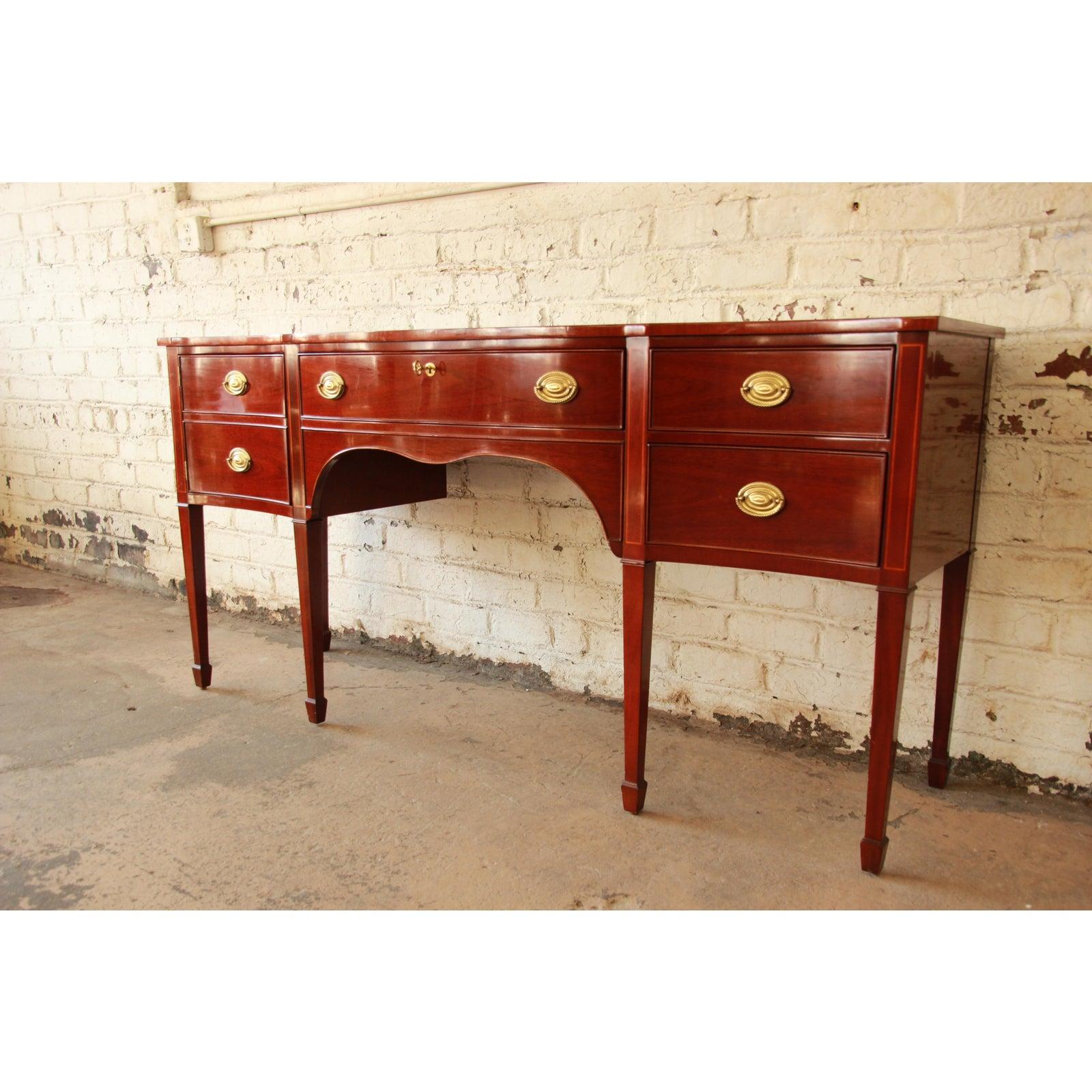 An exceptional inlaid mahogany sideboard buffet from the Winterthur Collection by Kindel Furniture. The sideboard features a traditional Hepplewhite style, with tall tapered legs and spade feet. It has original brass hardware and is well built with