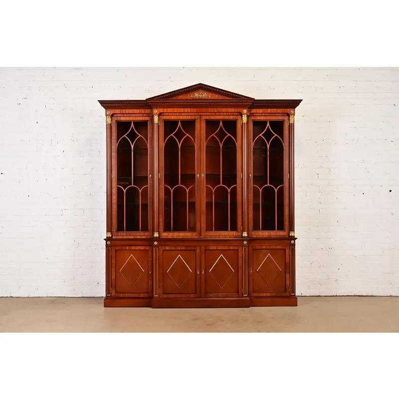 A gorgeous Neoclassical, Regency, or French Empire style breakfront bookcase or dining cabinet

By Kindel Furniture

USA, Circa 1980s

Carved mahogany, with mullioned glass front doors, mounted brass trim and ormolu, and brass hardware. Interior