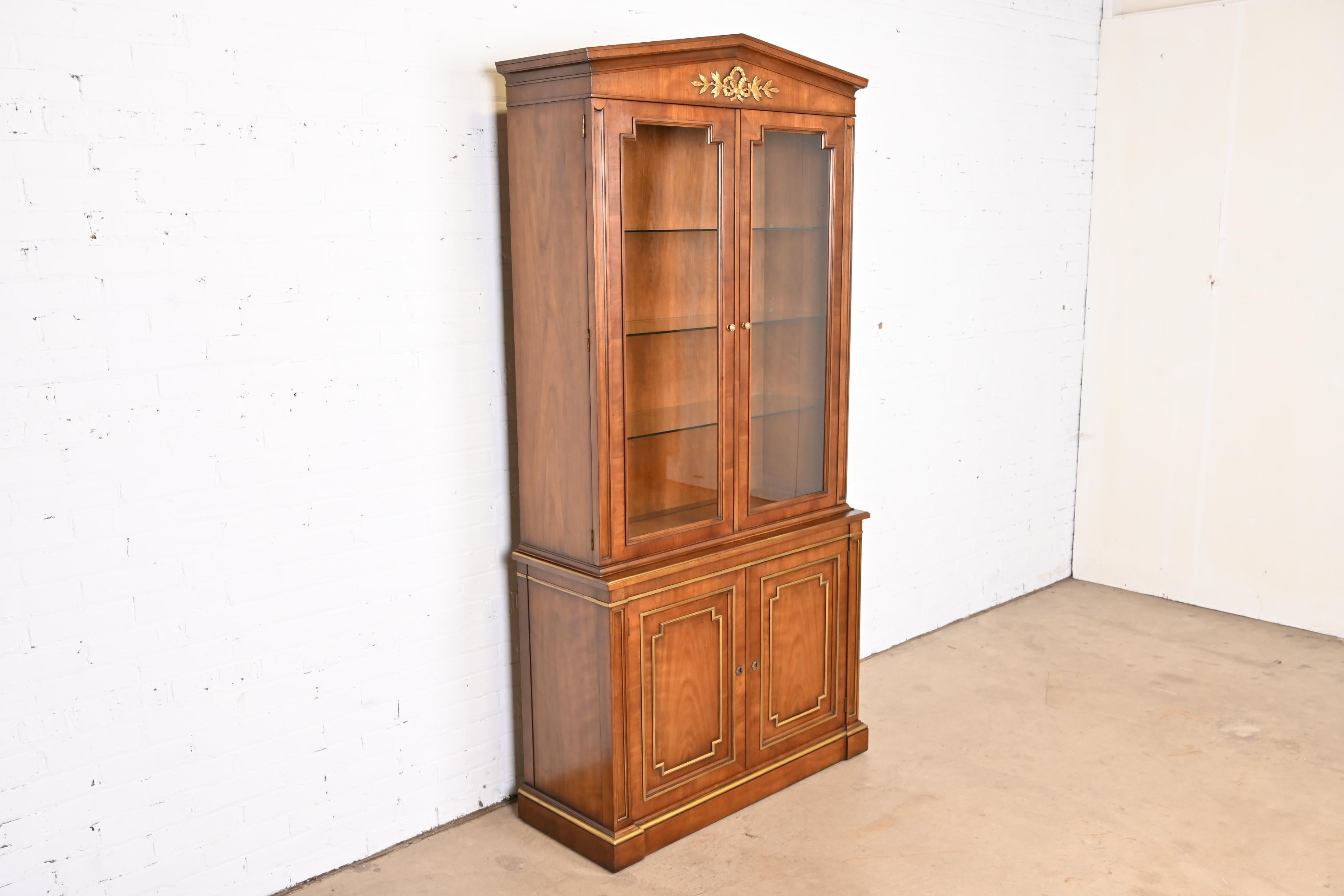 A gorgeous Neoclassical or Regency style lighted breakfront bookcase or dining cabinet

By Kindel Furniture

USA, 1970s

Gorgeous book-matched cherry wood, with gold gilt details and glass front doors.

Measures: 40.38