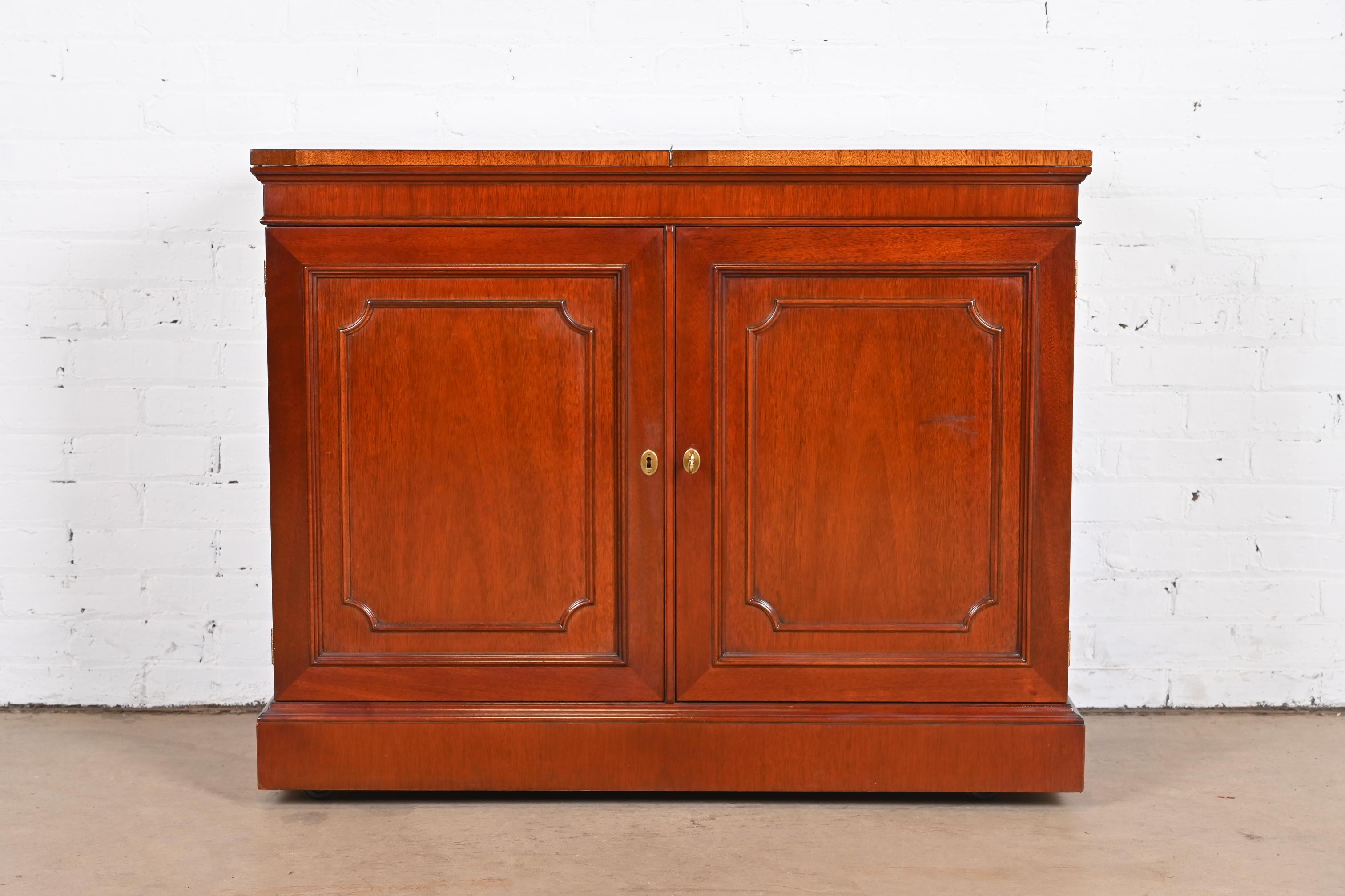 A gorgeous Regency or Georgian style flip-top rolling bar cabinet

By Kindel Furniture

USA, Circa 1980s

Carved mahogany, with original brass hardware. Cabinet locks, and key is included.

Measures: 40.5