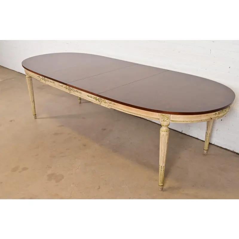 Una excepcional mesa de comedor extensible estilo Luis XVI de la Regencia francesa

A la manera de Kindel Furniture

EE.UU., alrededor de 1960

Preciosa encimera de nogal burilado a juego con el libro, con faldón y patas lacadas en crema y verde