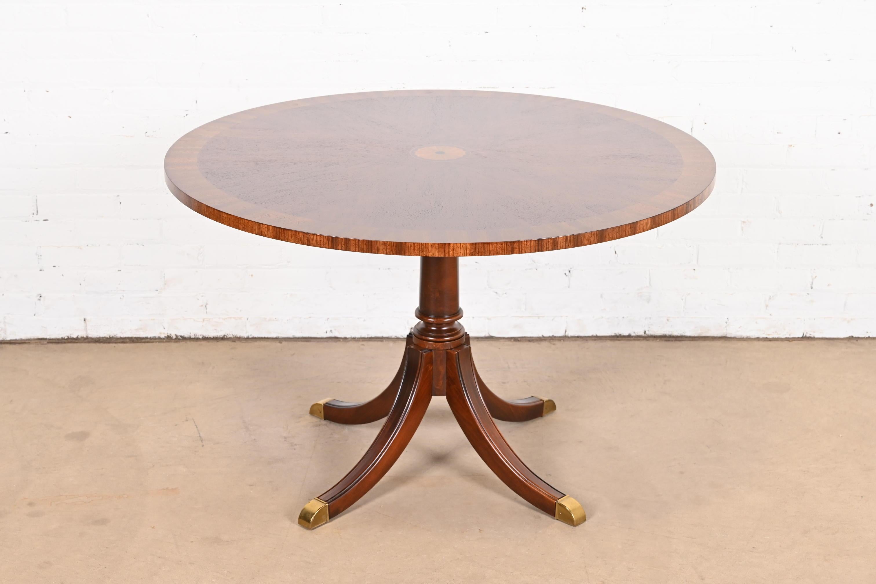 An exceptional Georgian or Regency style pedestal dining table, center table, or breakfast table

In the manner of Kindel Furniture

USA, Circa 1980s

Gorgeous book-matched mahogany, with inlaid satinwood marquetry, and carved solid mahogany