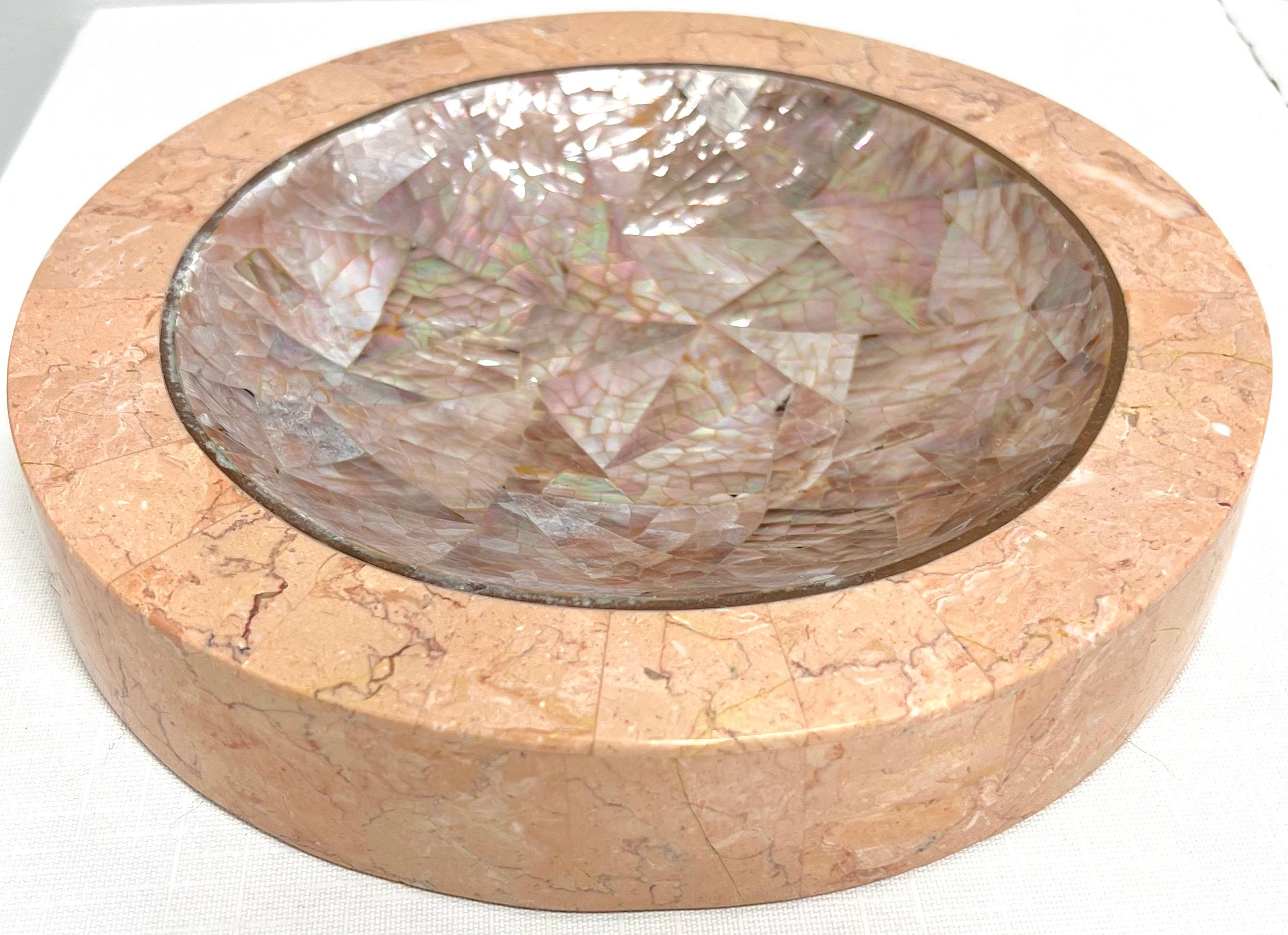 A decorative catchall bowl in tessellated stone by Dara, a division of Kinder-Harris. Base is shades of pink colored tessellated stone tiles in a round shade, recessed interior is shades of amethyst colored patterned tessellated stone tiles, and a