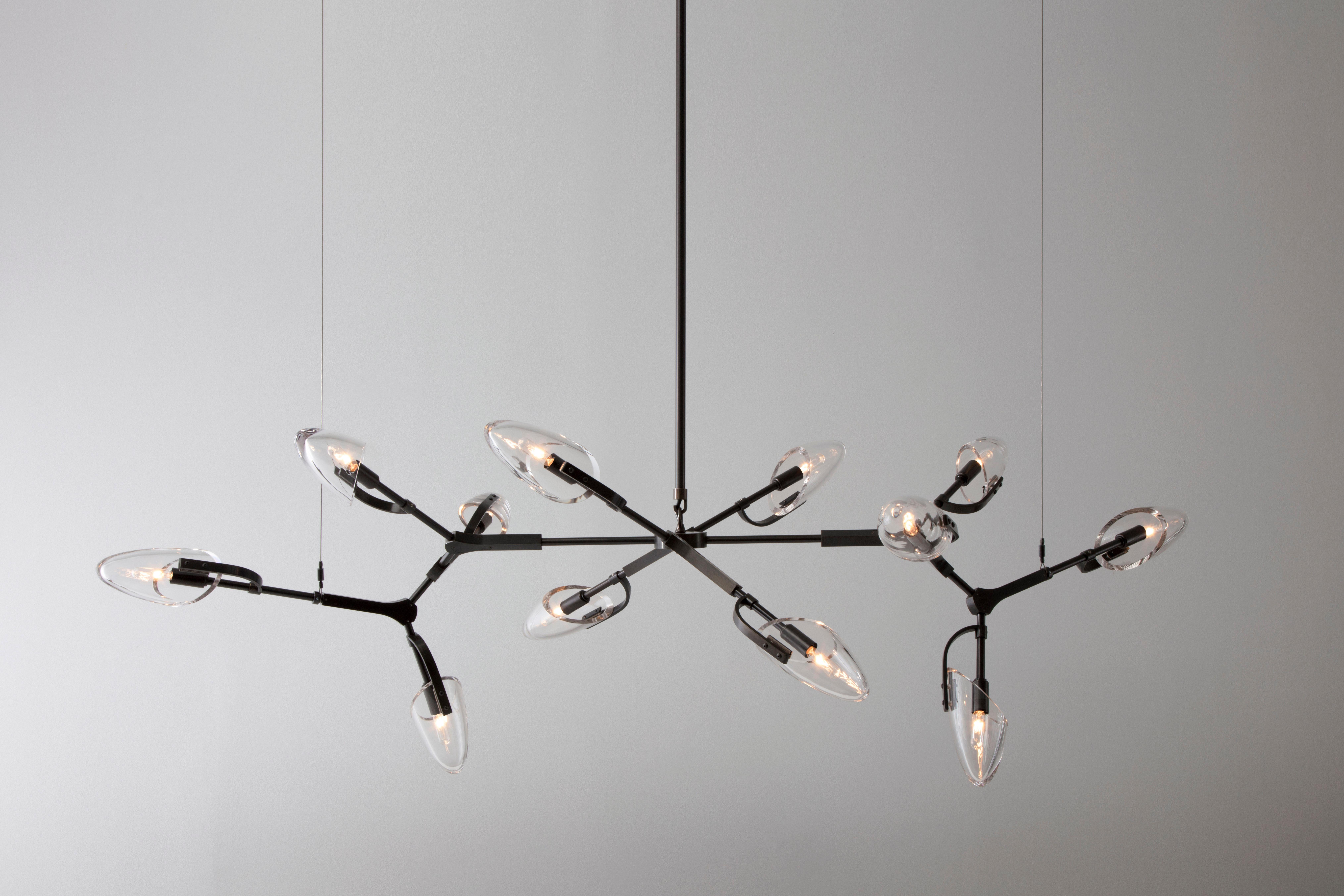 Kinesis chandelier is a modular lighting system featuring blown glass diffusers which are interconnected by solid brass components. The resulting fixture is a lithe and sculptural centerpiece, which is unique from every angle. This listing features