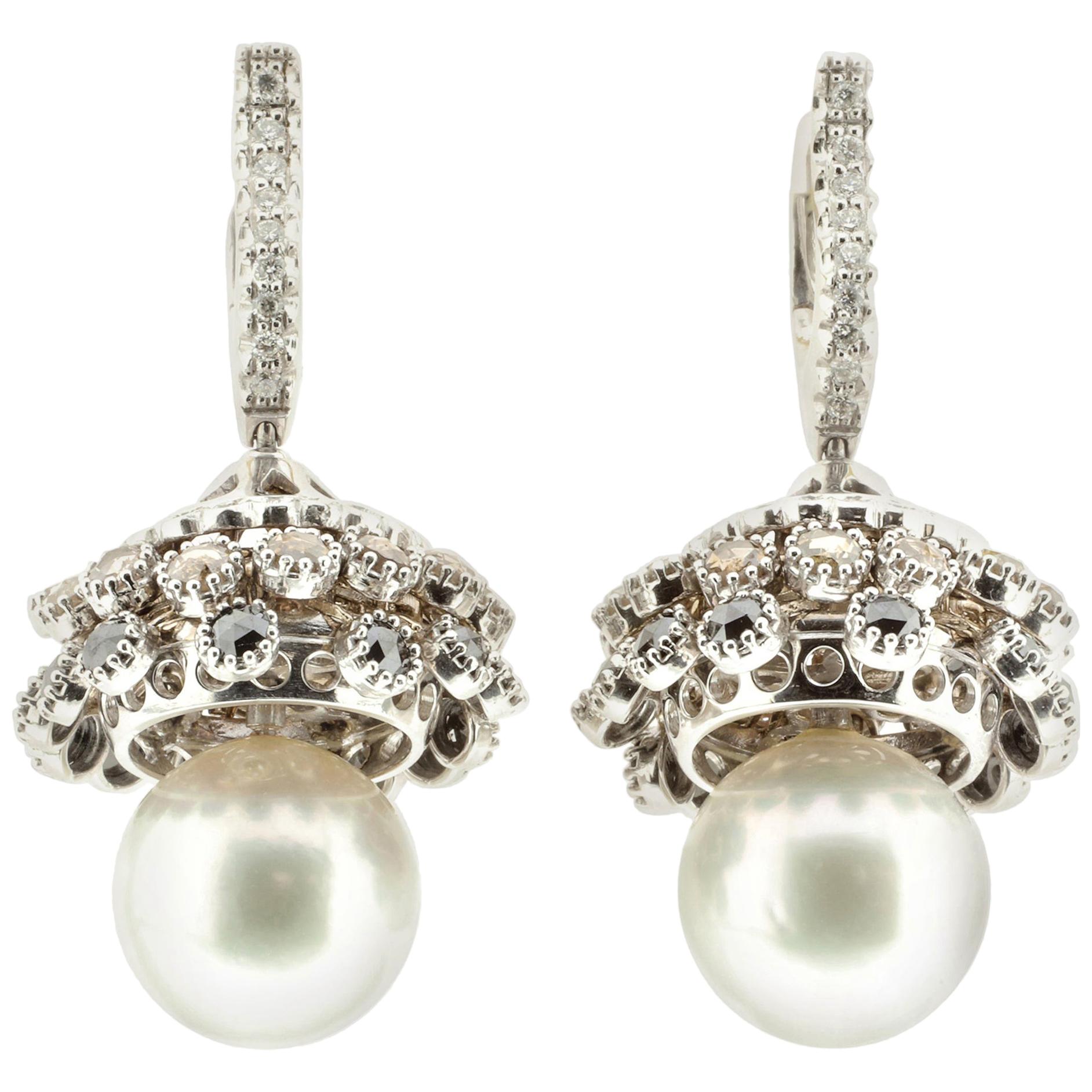 These earrings, made with two large Australian pearls, feature white diamonds rated G VS as well as rose-cut black and brown diamonds. The diamonds are set into 18-karat white gold setting, which shifts and moves with custom hinges. 

The pearls