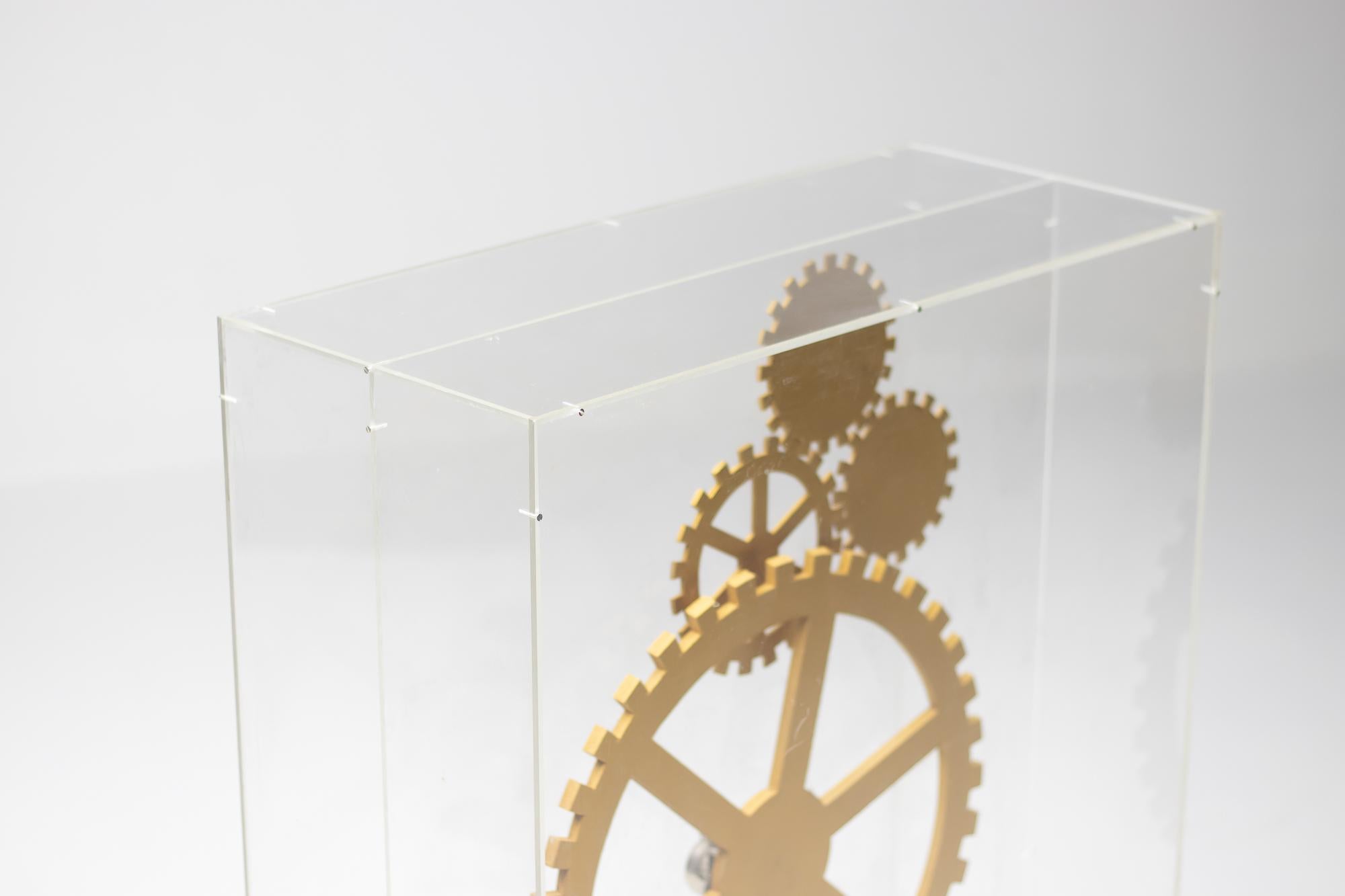 Grande œuvre d'art moderne intéressante sur le thème du temps qui passe.
Boîte en plexiglas contenant une composition de rouages en bois magnifiés et recouverts d'or, tels qu'ils sont utilisés dans les montres et les horloges.
Le grand rouage tourne