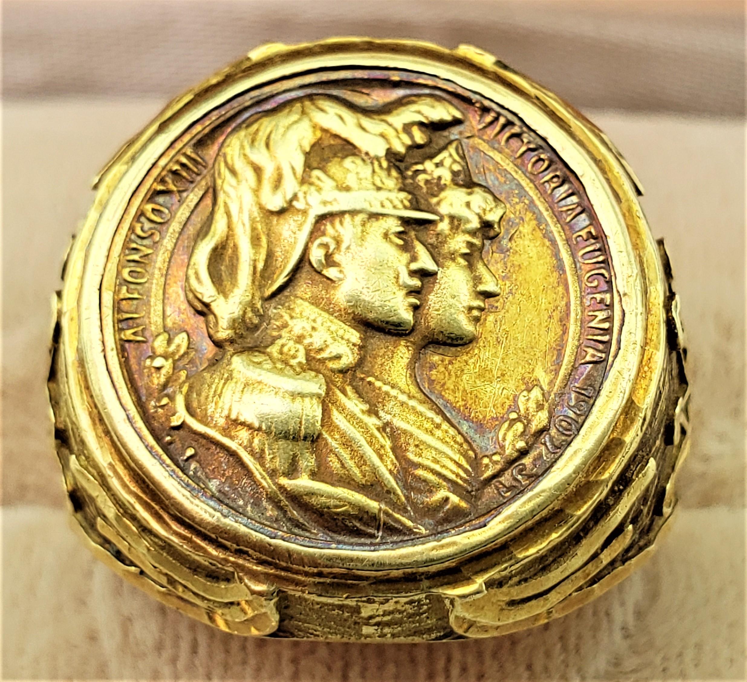 This vintage gold ring is unsigned and not marked, but believed to have originated from England and date to approximately 1935. The ring tests for a minimum of eighteen karat yellow gold and has an inset medallion of King Alphonso XIII and Queen