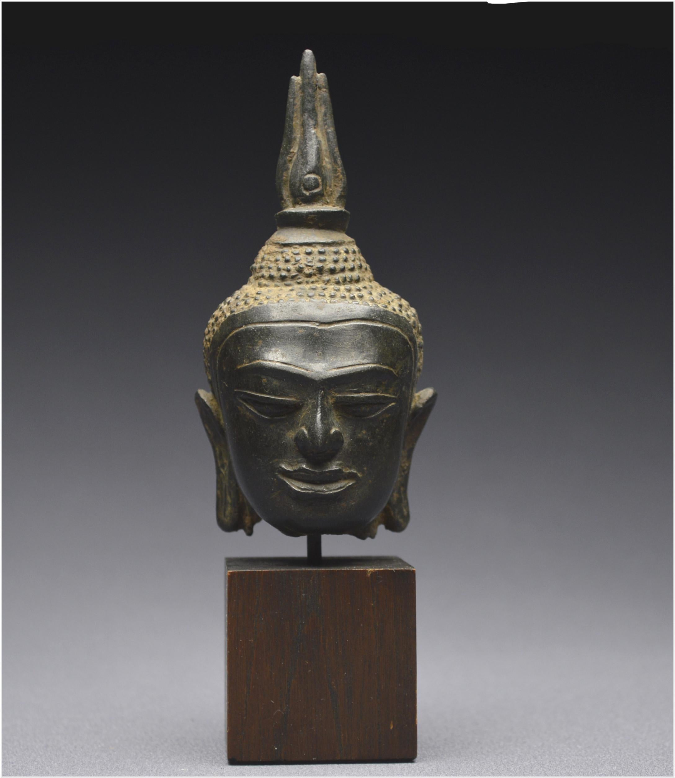 Ancient Kingdom of Siam (current Thailand)
U-Thong B style
14th - 15th century

Small Buddha head with dark patina. The face with majestic severity, the result of a stylistic syncretism mixing in a subtle dosage influences from Sukhotai, Dvaravati,