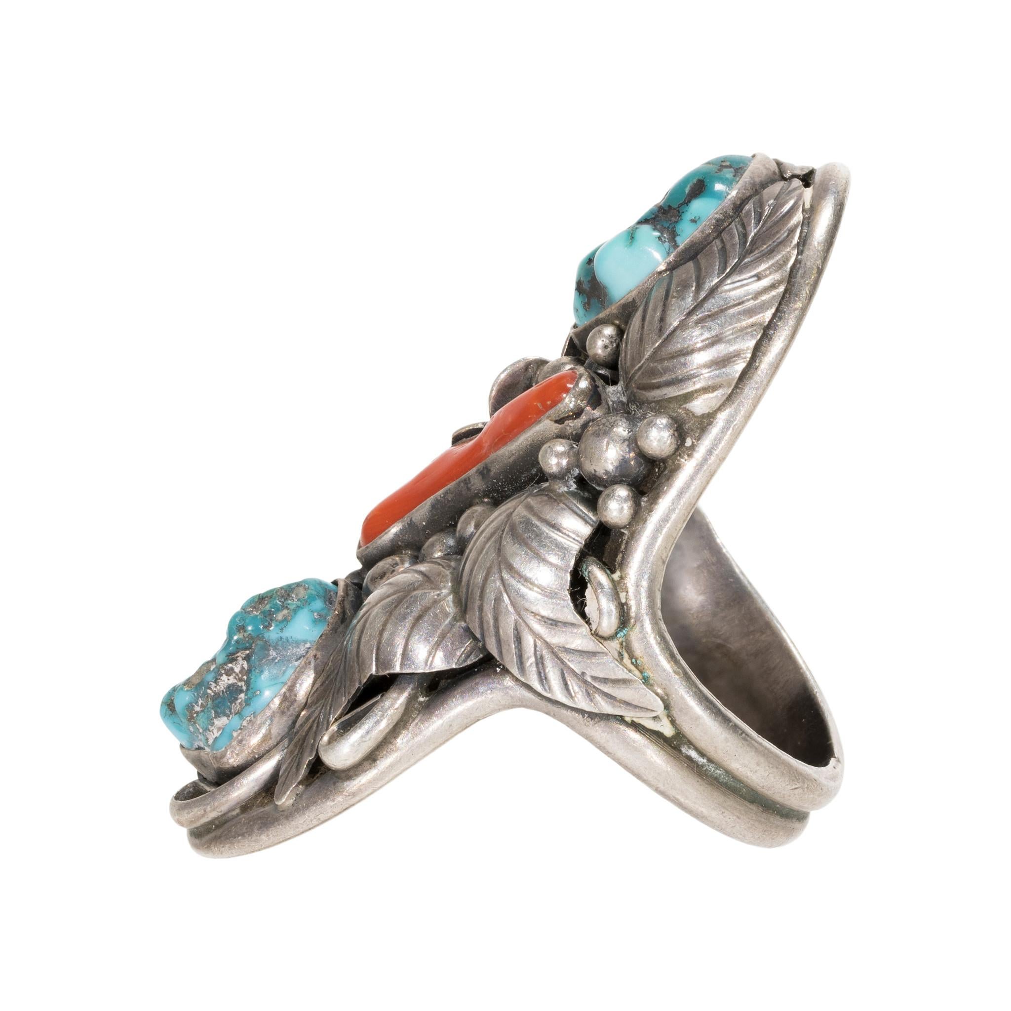 Kingman turquoise and coral ring on sterling silver. Kingman stones at top and bottom with coral branch in center. Stones are encased in exceptional floral, leaf, and sterling bead design. Setting is slightly domed. Beautiful statement piece, great