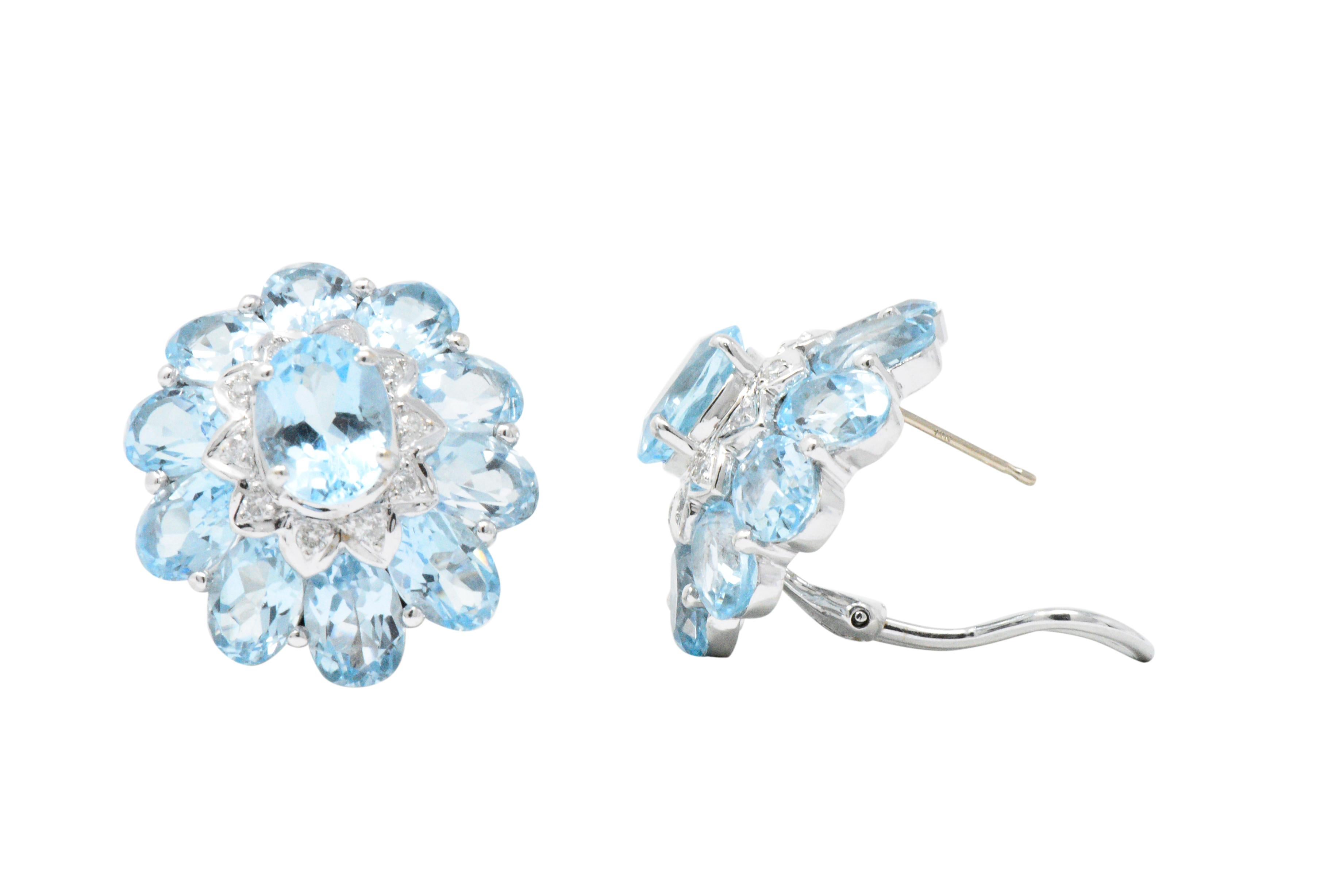 Cluster motif centering an oval cut blue topaz with an outer oval cut blue topaz surround, approximately 26.50 carats total for both earrings, bight light blue, very well matched

Between the outer and center blue topaz is a round brilliant cut