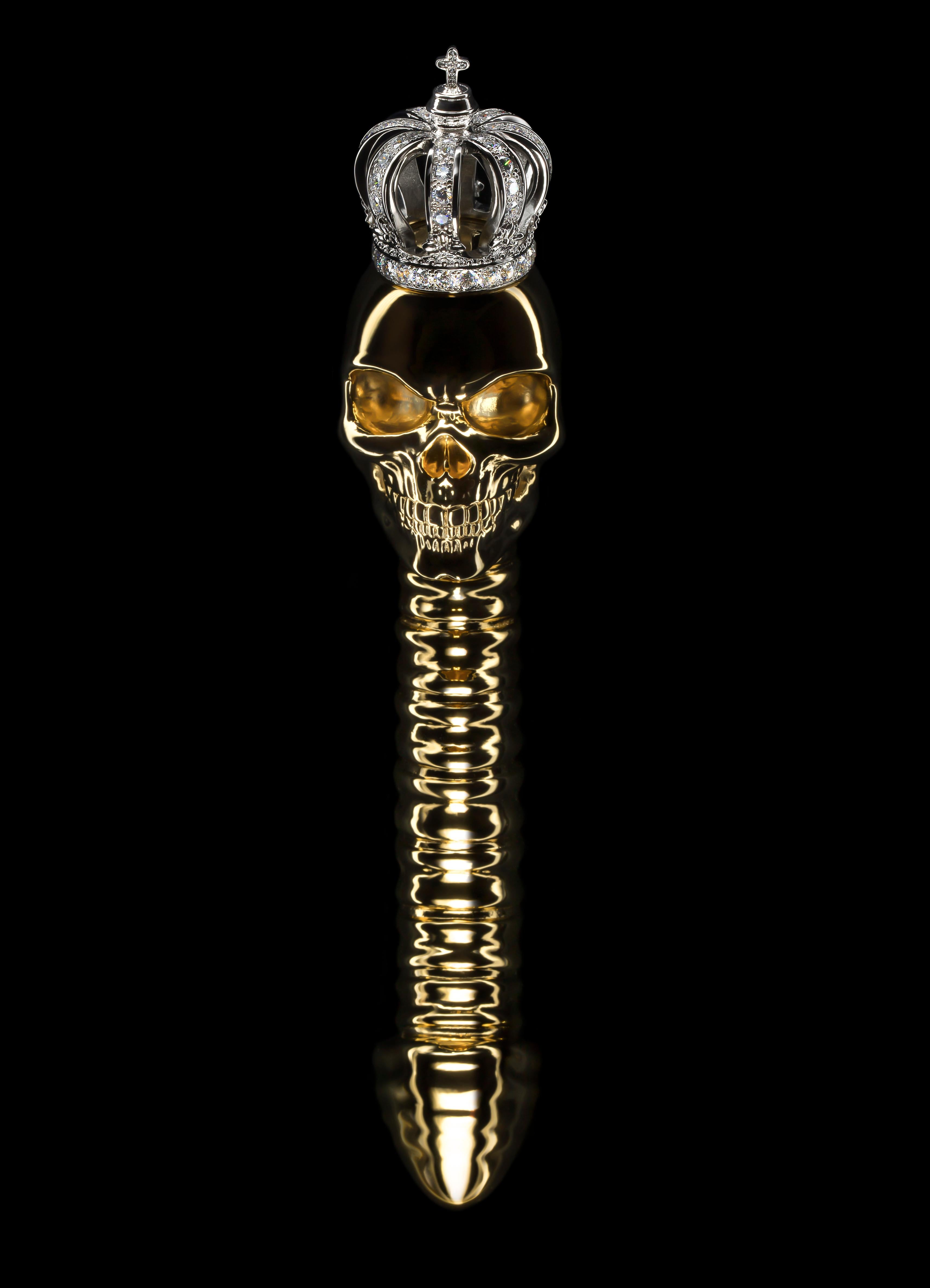 The Kings Remains olisbos sculpture is electroformed from pure 24K yellow gold. This skull and spinal sculpture features an 18K solid white gold regal crown, set with 10 carats of flawless sparkling white diamonds. The sculpture comes with a clear
