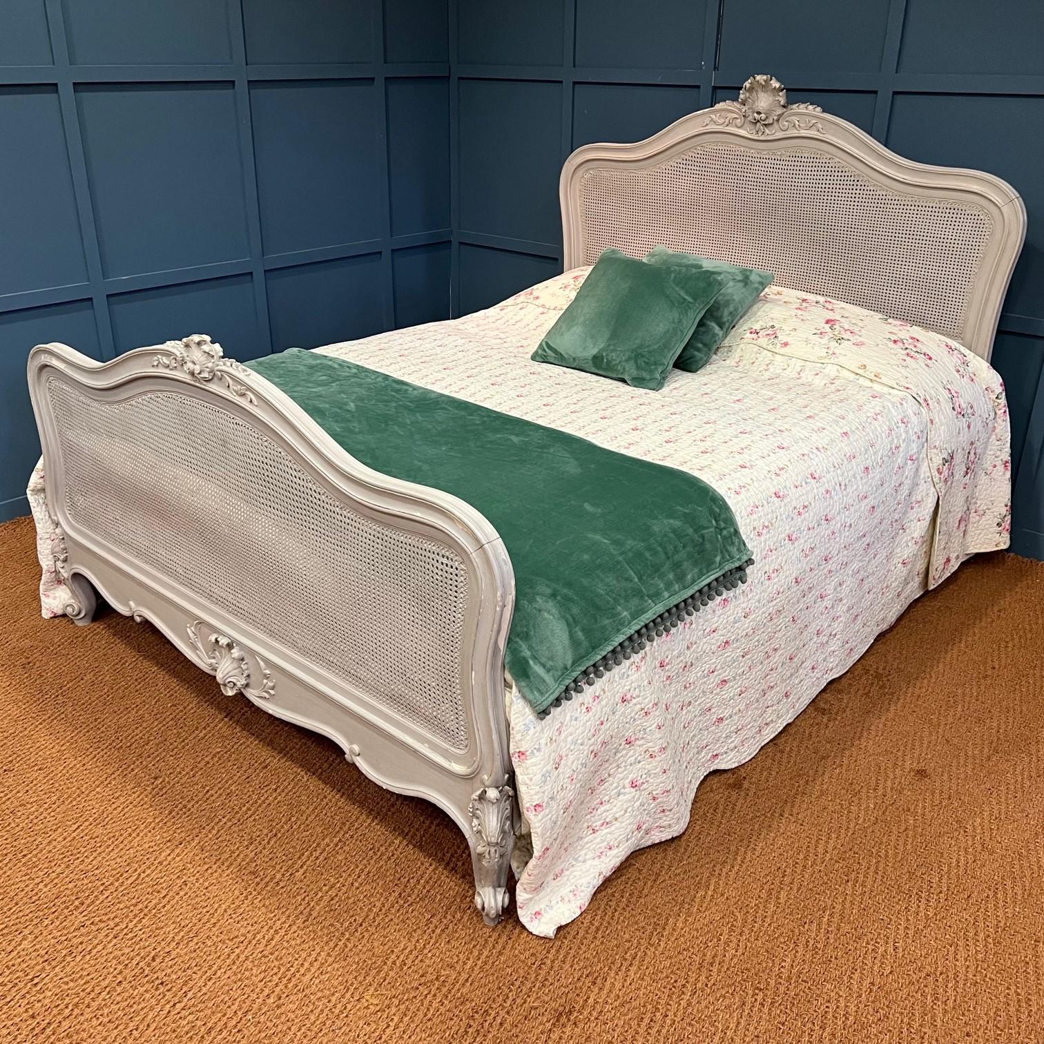 An antique French king size (5’ wide) painted caned bed – circa 1900. This is such a lovely bed – in the style of Louis XV. The frame has a large hand carved shell at the centre of the head and foot end along with decorative carved swirls and