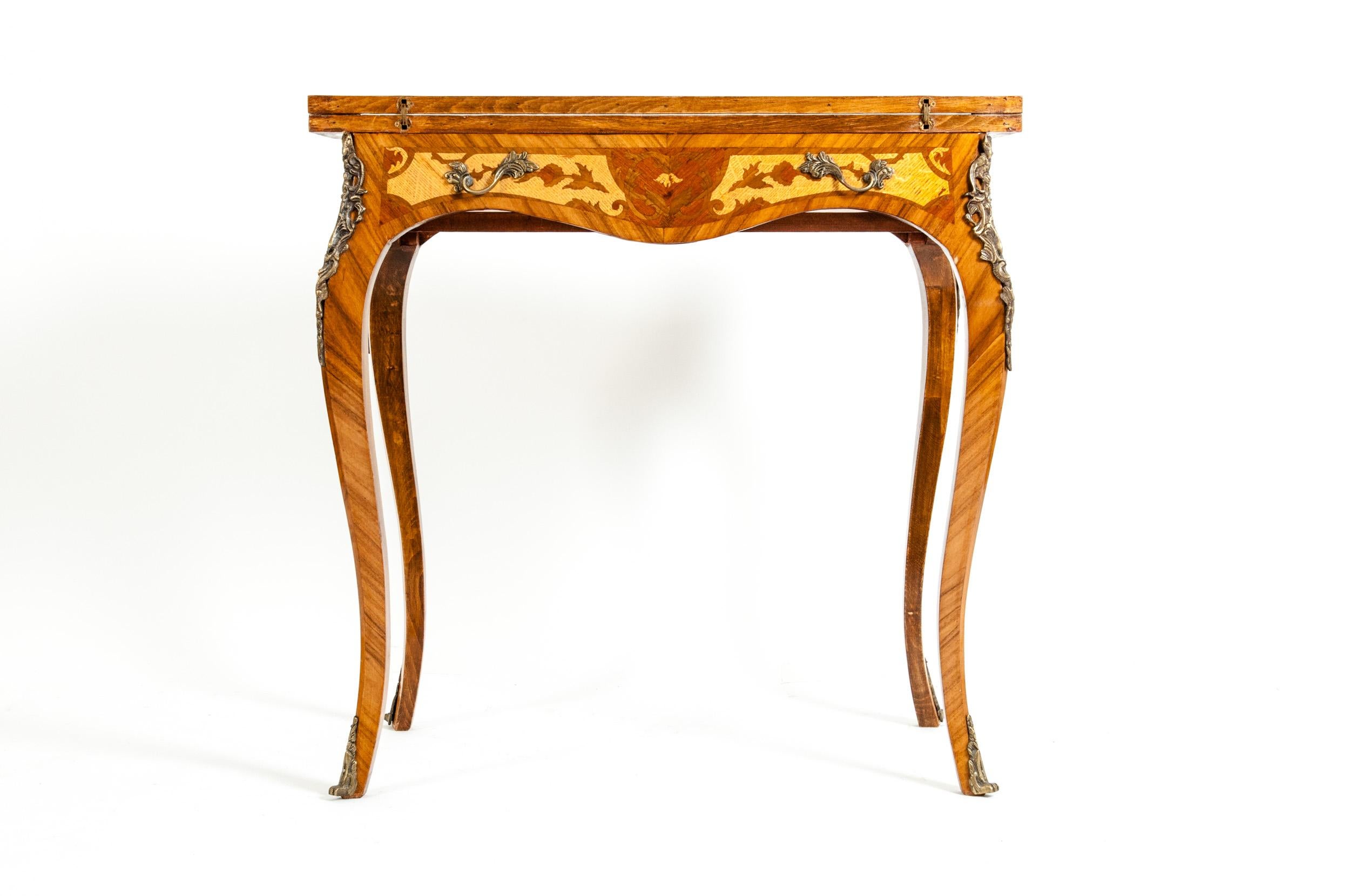 Kingwood mounted bronze design details card table with a shaped folding top above a serpentine frieze and elegant cabriole legs with gilt bronze foliate mounts, decorated overall with superb marquetry panels of cross-grained foliate scrolls against