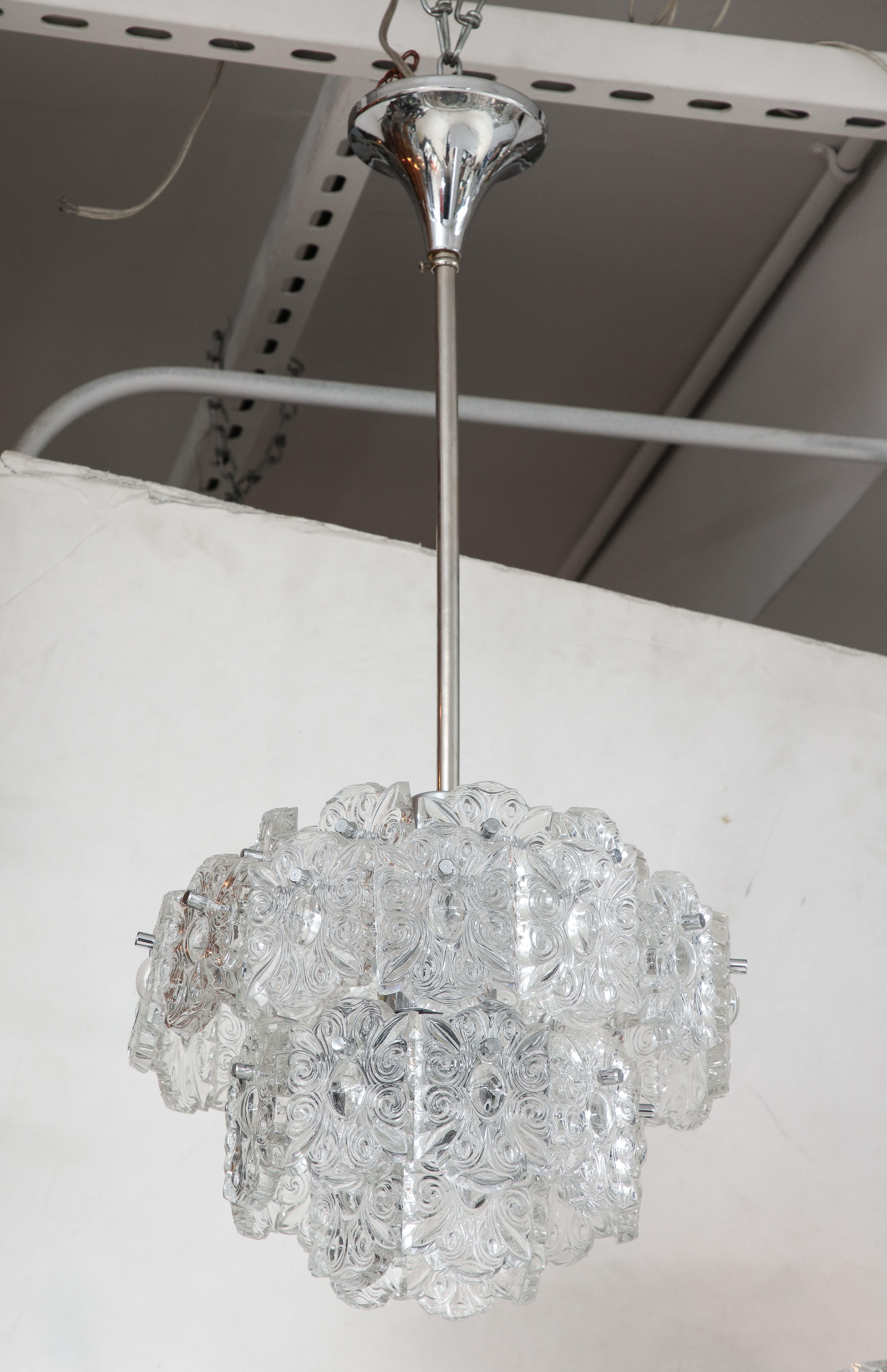 Lampadario moderno scandinavo a 4 livelli con cisti stilizzate oblunghe a forma di cammeo sospese da una struttura e da un baldacchino in nichel lucido. Ricablato per l'uso negli Stati Uniti, 7 prese.
