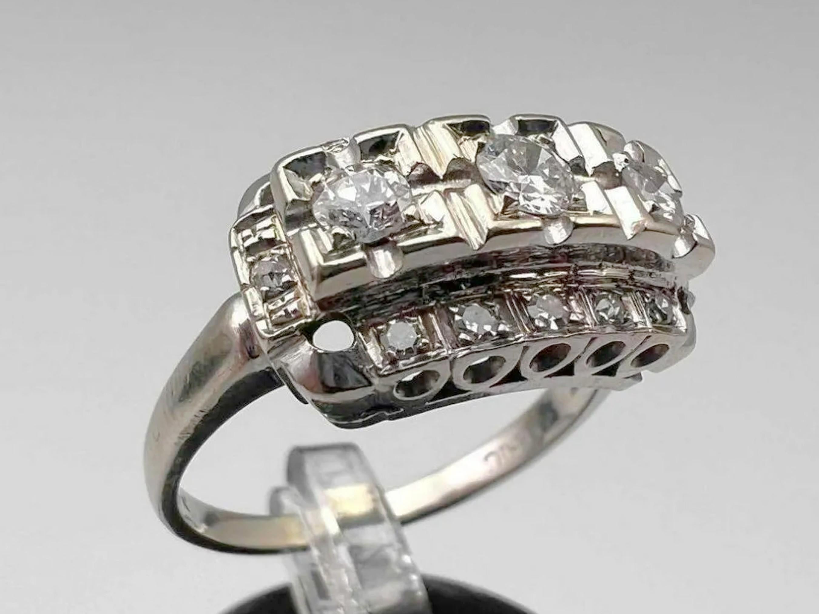 A stunning 15-diamond Art Deco vintage engagement ring set in 14k white gold. The ring face steps up to three prong-set round diamonds in square settings. Below are 5 diamonds in a row on either side, with a further stone on each shoulder.