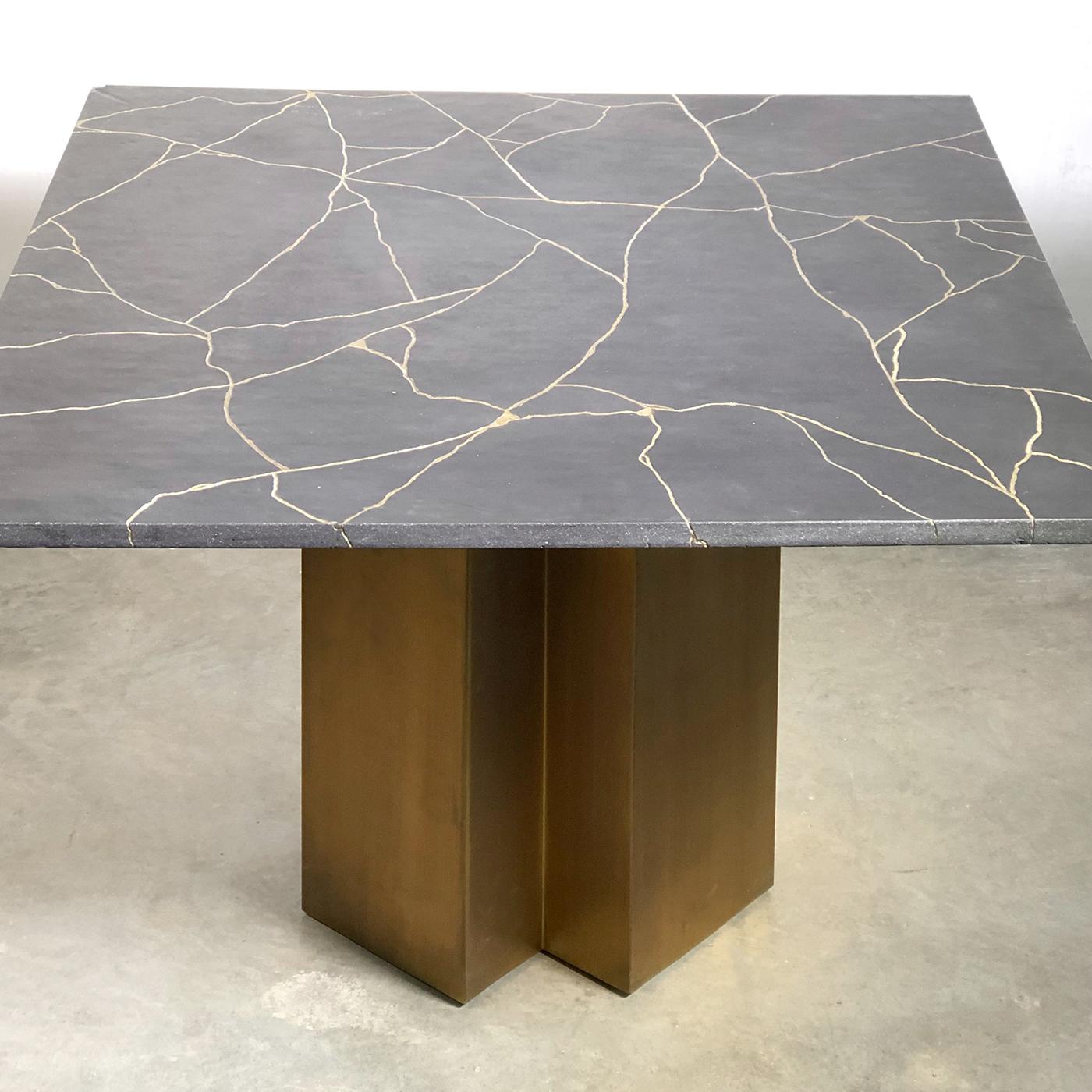 Named after the Japanese art of repairing broken pottery with precious metal to emphasize the imperfections, this superb coffee table will infuse elegance in a modern interior. Its sculptural bronze base supports a square surface made with the