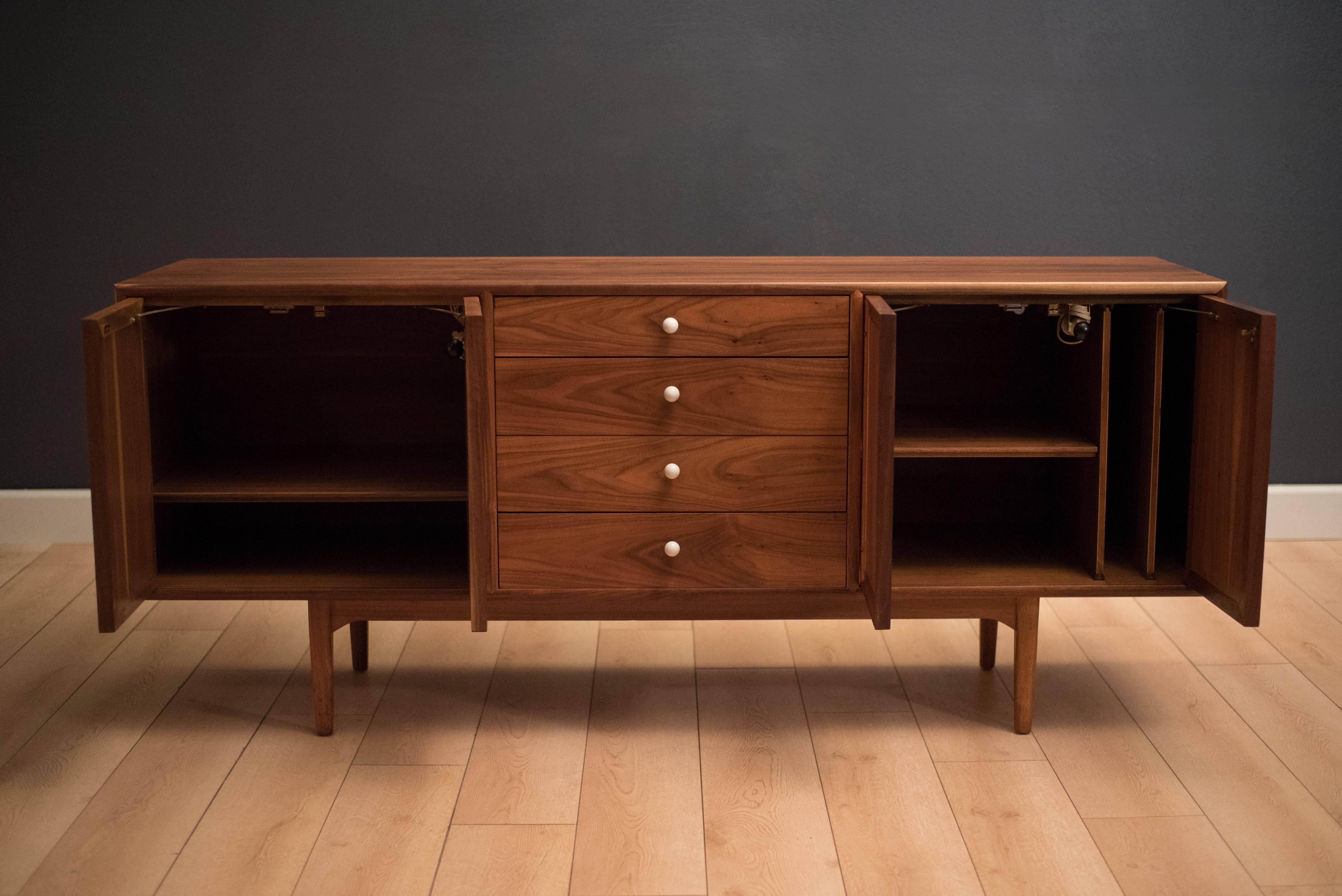 Mid century Drexel declaration sideboard credenza by Kipp Stewart and Stewart MacDougall. This piece features bookmatched black walnut grains highlighted by their signature white porcelain pulls. Equipped with four drawers and open storage with