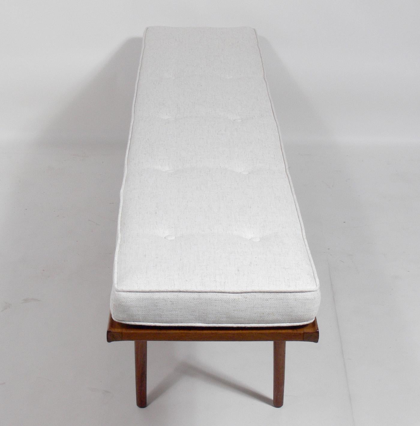 Clean lined midcentury walnut bench, designed by Kipp Stewart for Drexel, American, circa 1950s. It is a versatile size and can be used as a coffee table or bench. Beautiful graining to the walnut top. Reupholstered in an ivory color herringbone