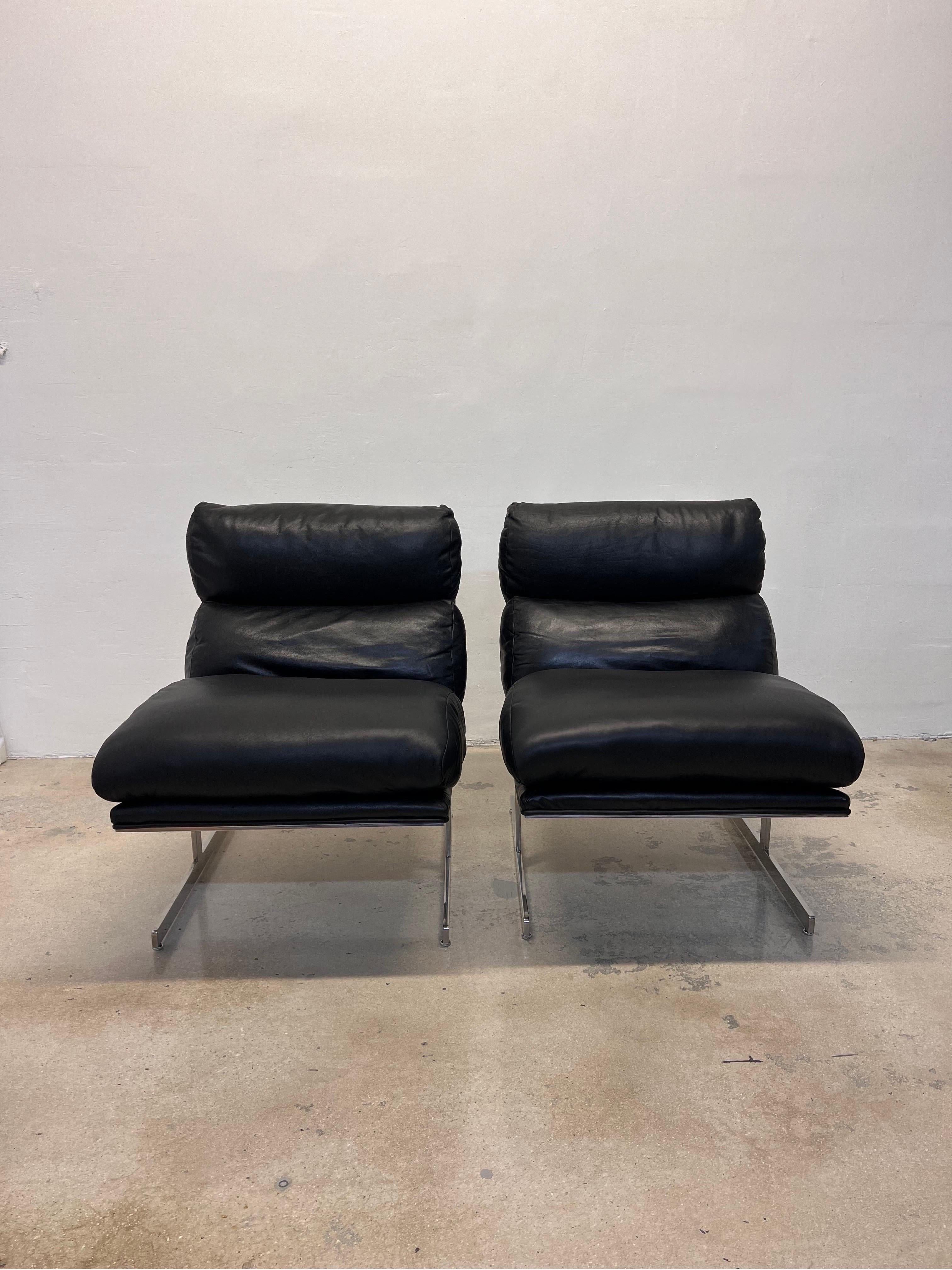 Pair of black leather and chrome Arc lounge chairs designed by Kipp Stewart and manufactured by Directional. 

The leather backrest and leather covered frame are original. The leather seat has been reupholstered with new leather and foam/down