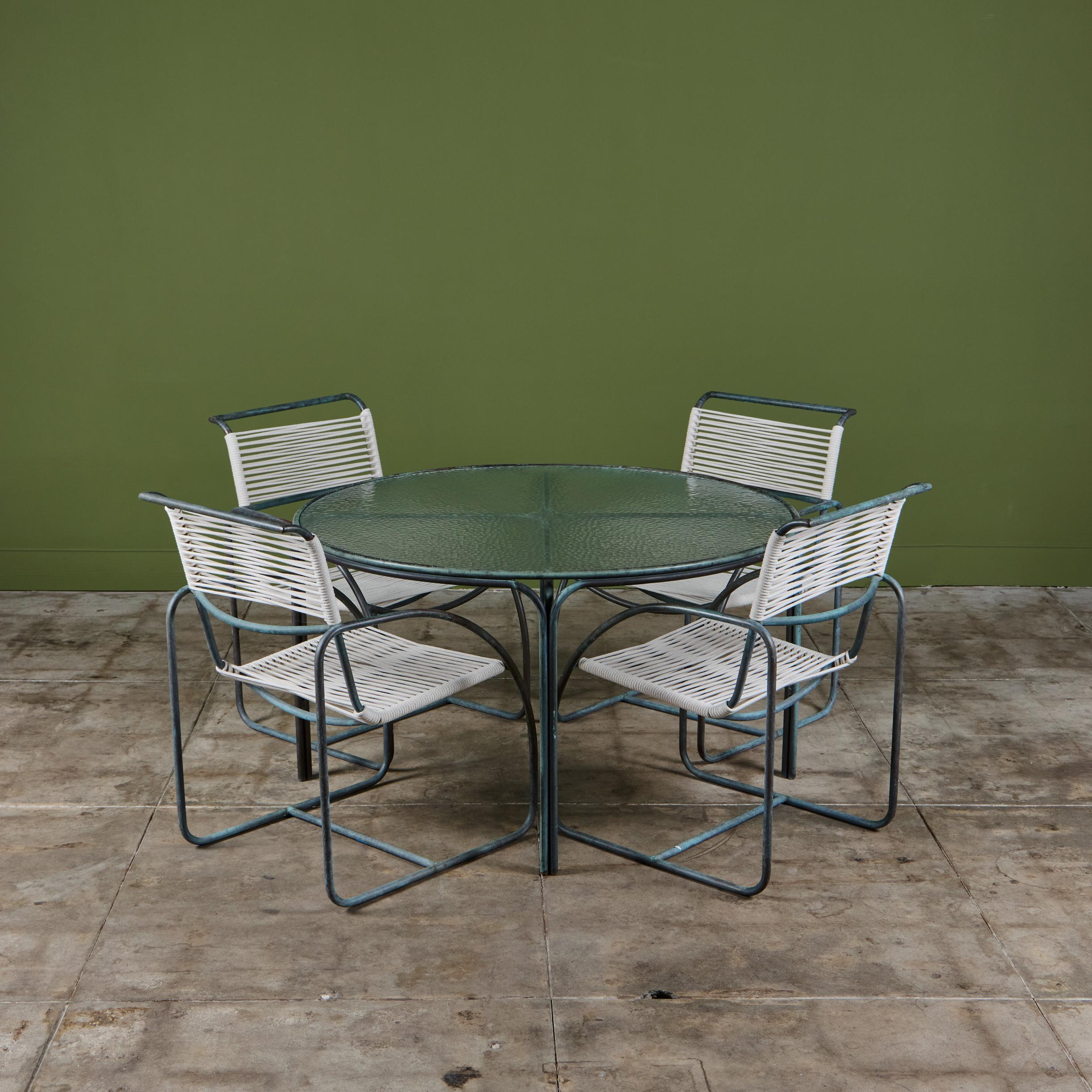 Patio dining set by Kipp Stewart for Terra of California, USA, c.1970s. The set features four patinated bronze tube framed armchairs with matching bronze table, with original pebble glass top. The chairs feature new cotton rope that has been woven