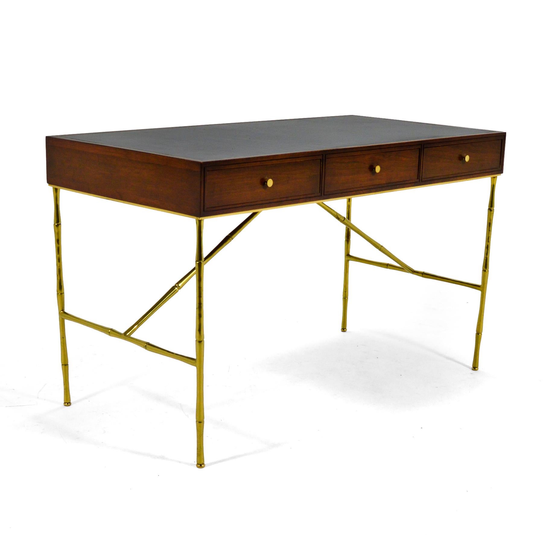 This is simply a stunning Kipp Stewart design executed beautifully by Directional. The wonderfully proportioned desk features a rich wood case with a leather inlaid top that is supported by legs of brass shaped like bamboo. It has three deep leather