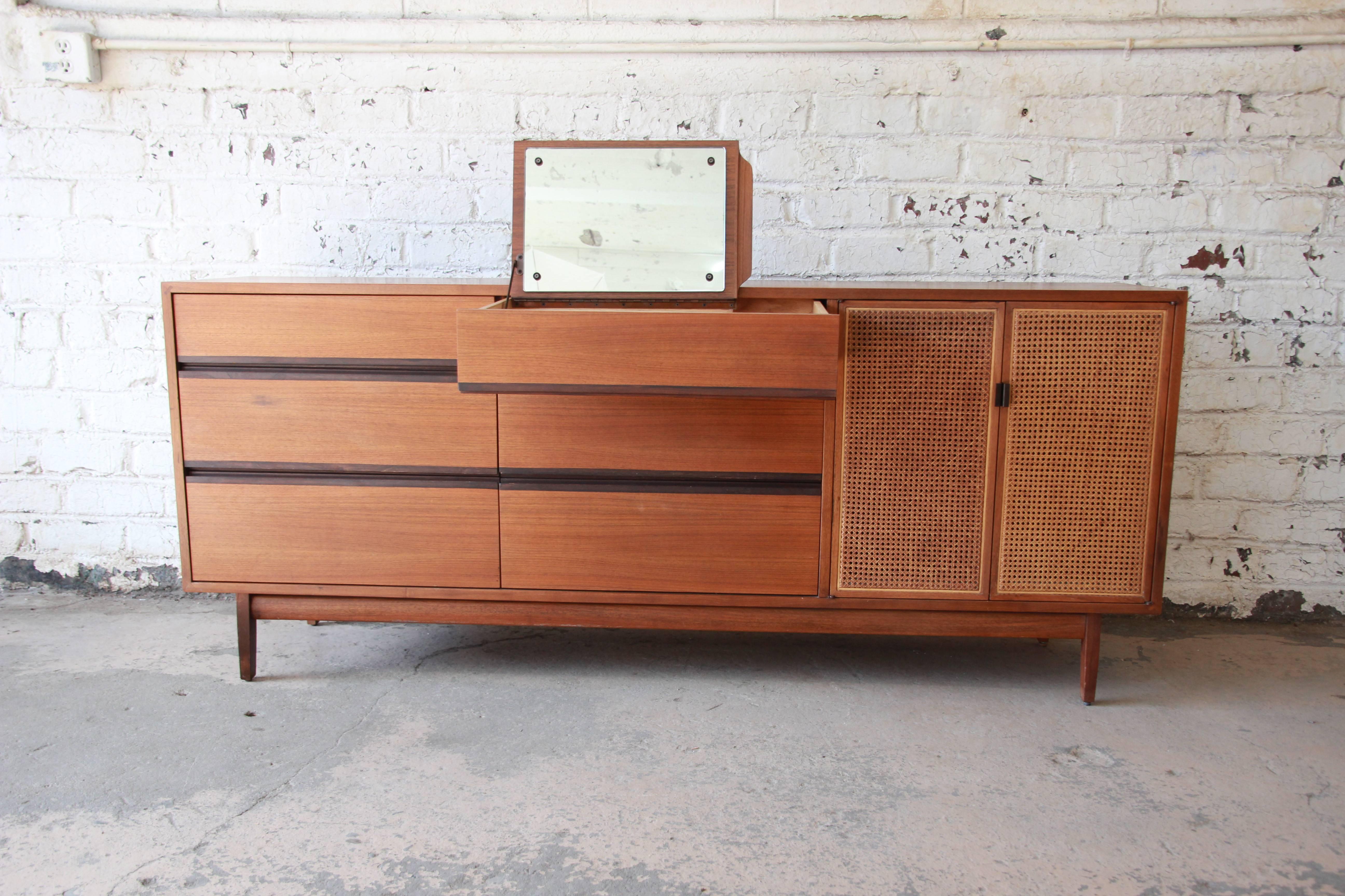 A gorgeous Mid-Century Modern walnut and cane dresser or credenza designed by Kipp Stewart for his American Design Foundation line for Calvin Furniture, circa 1950s. The dresser features gorgeous walnut wood grain and sleek Mid-Century Modern