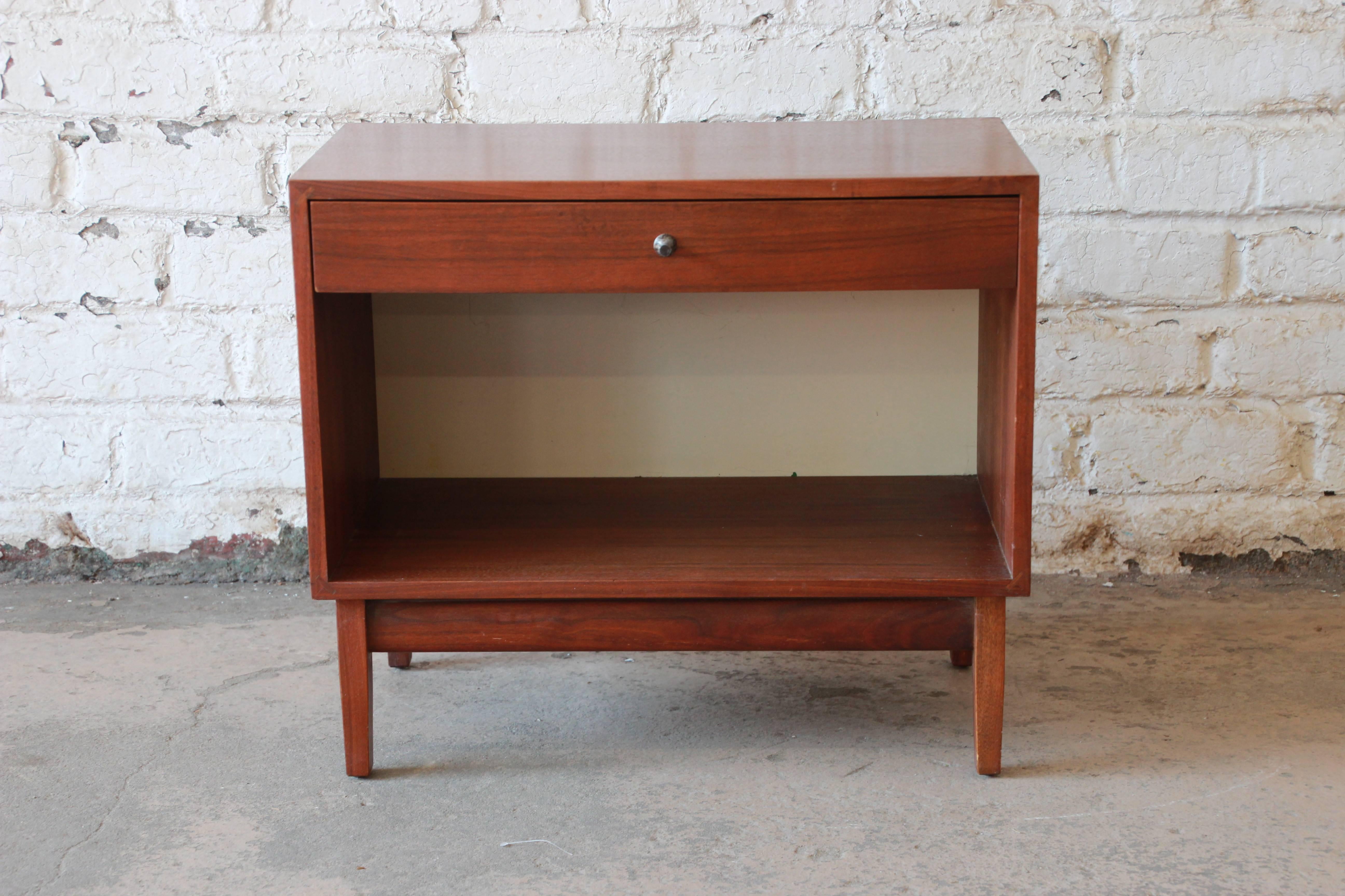 An outstanding Mid-Century Modern walnut nightstand designed by Kipp Stewart for his American Design Foundation line for Calvin Furniture, circa 1950s. The nightstand features gorgeous walnut wood grain and sleek mid-century design. It offers good