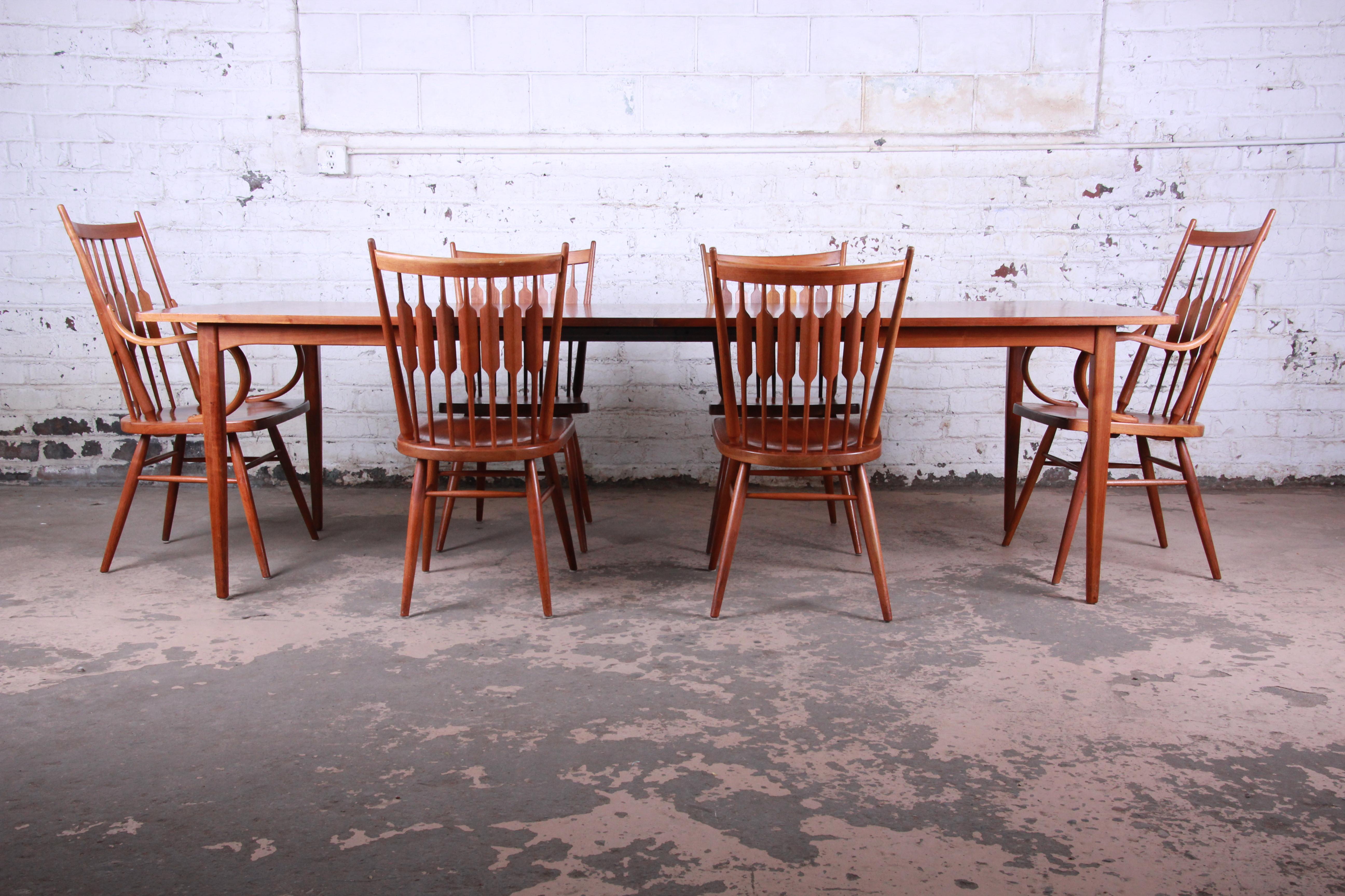 A gorgeous Mid-Century Modern walnut extension dining table and chairs designed by Kipp Stewart for his declaration line for Drexel. The set includes the table, two leaves, two captain armchairs, and four side chairs. The table features stunning