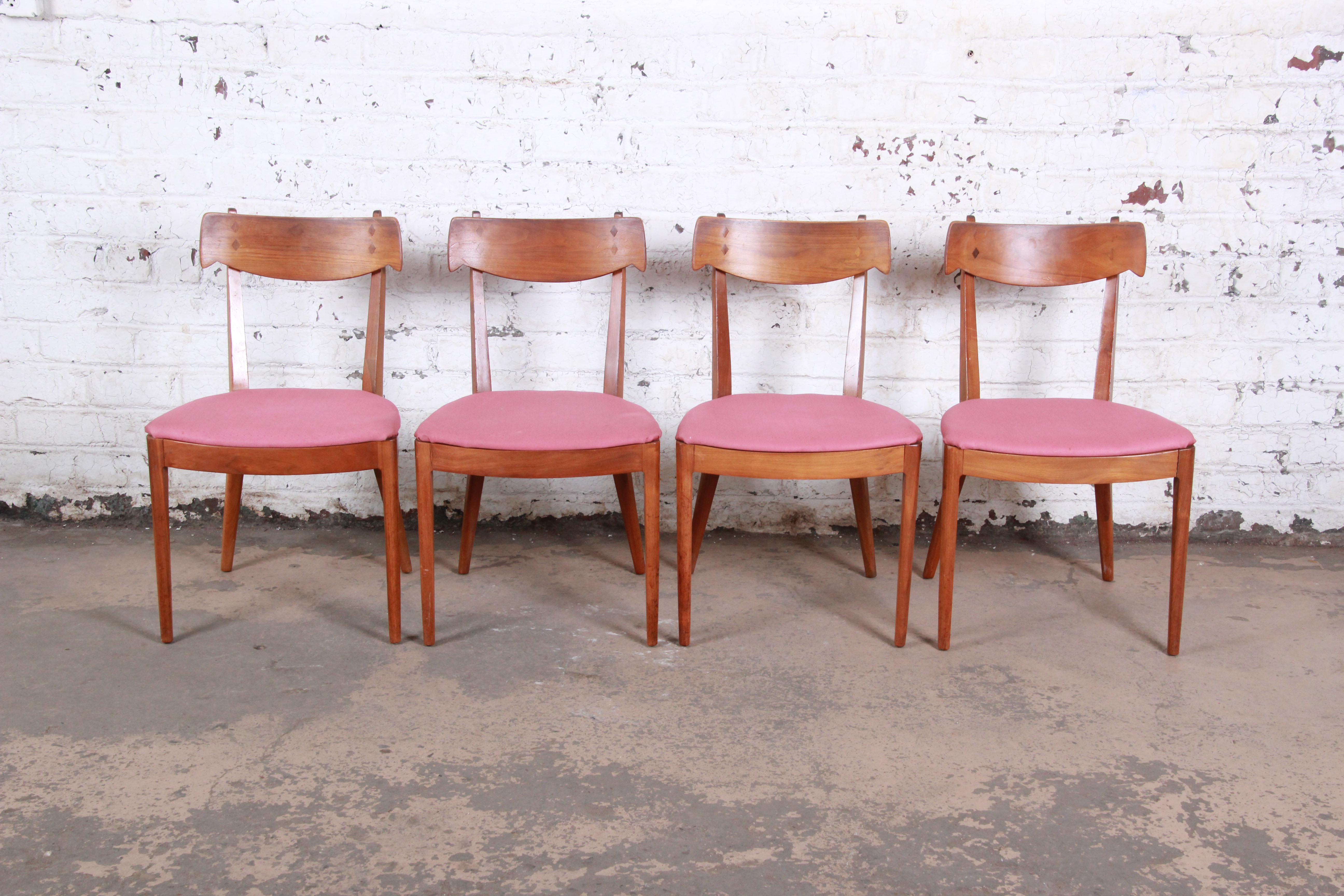 A stylish set of four Mid-Century Modern dining chairs designed by Kipp Stewart for his declaration line for Drexel Furniture. The chairs features gorgeous sculpted walnut frames with subtle curves and details. The pink upholstery could easily be
